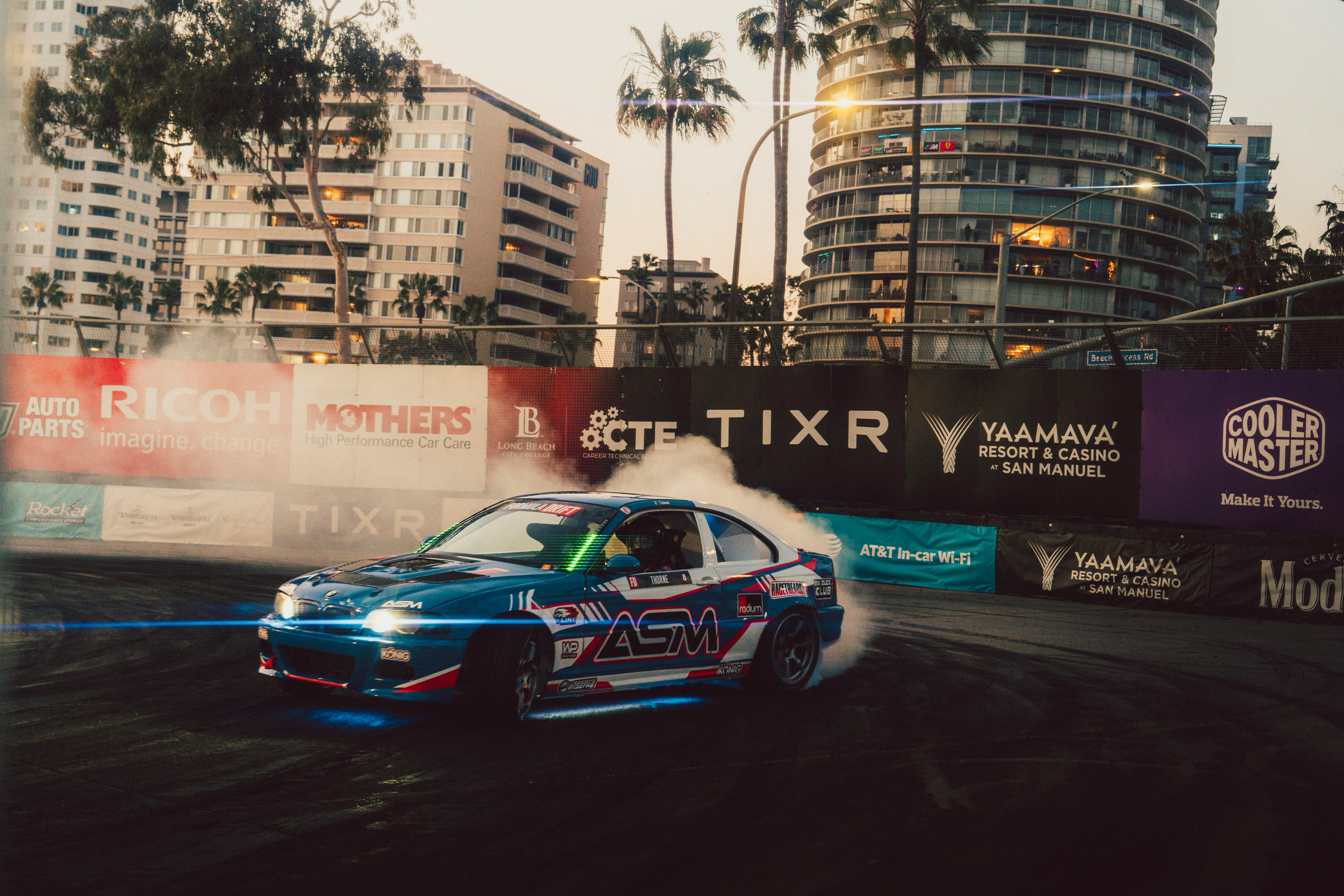 Drifting car emitting smoke on a city street.