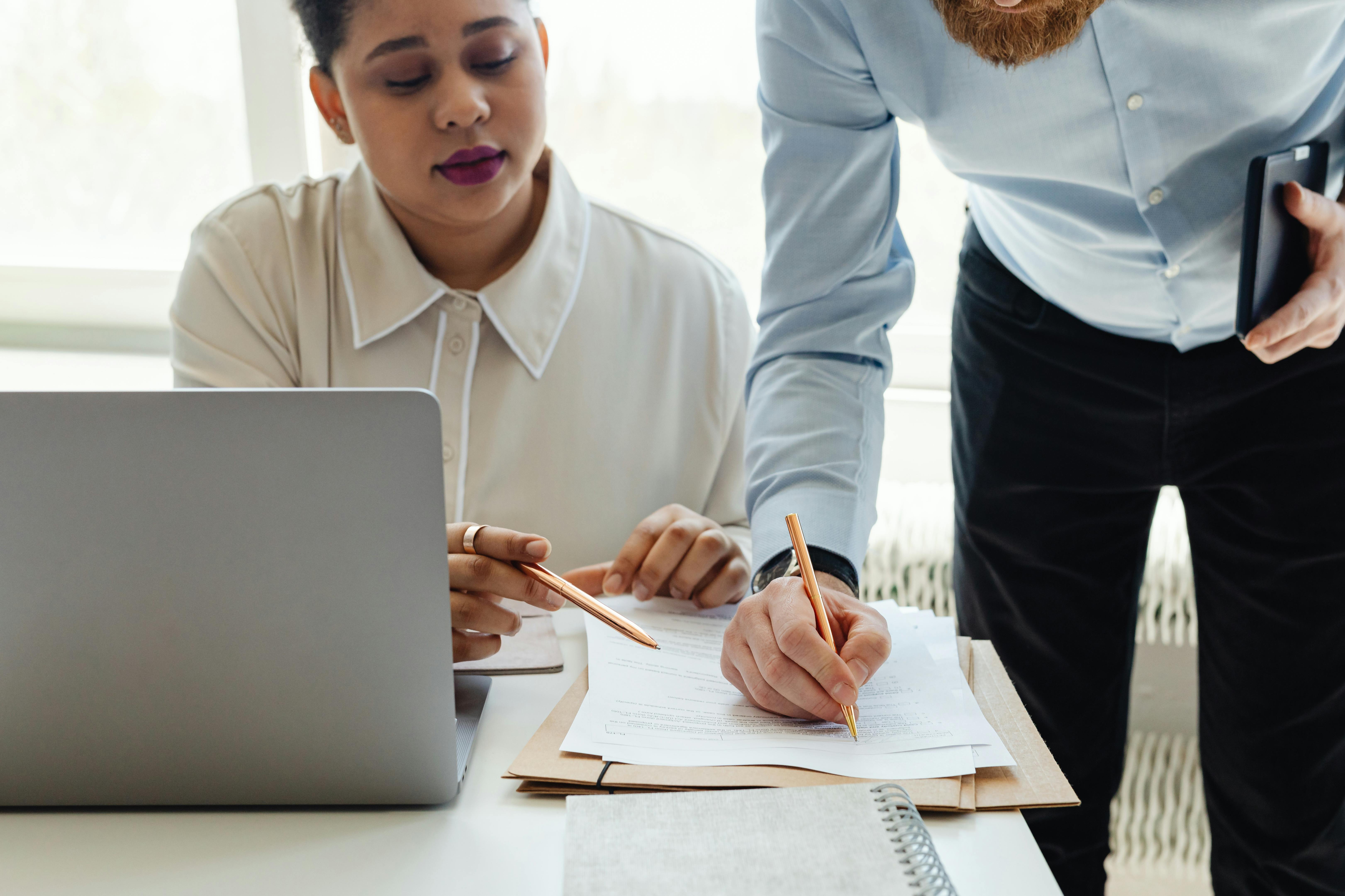 A man and a woman in an office reviewing a paper document