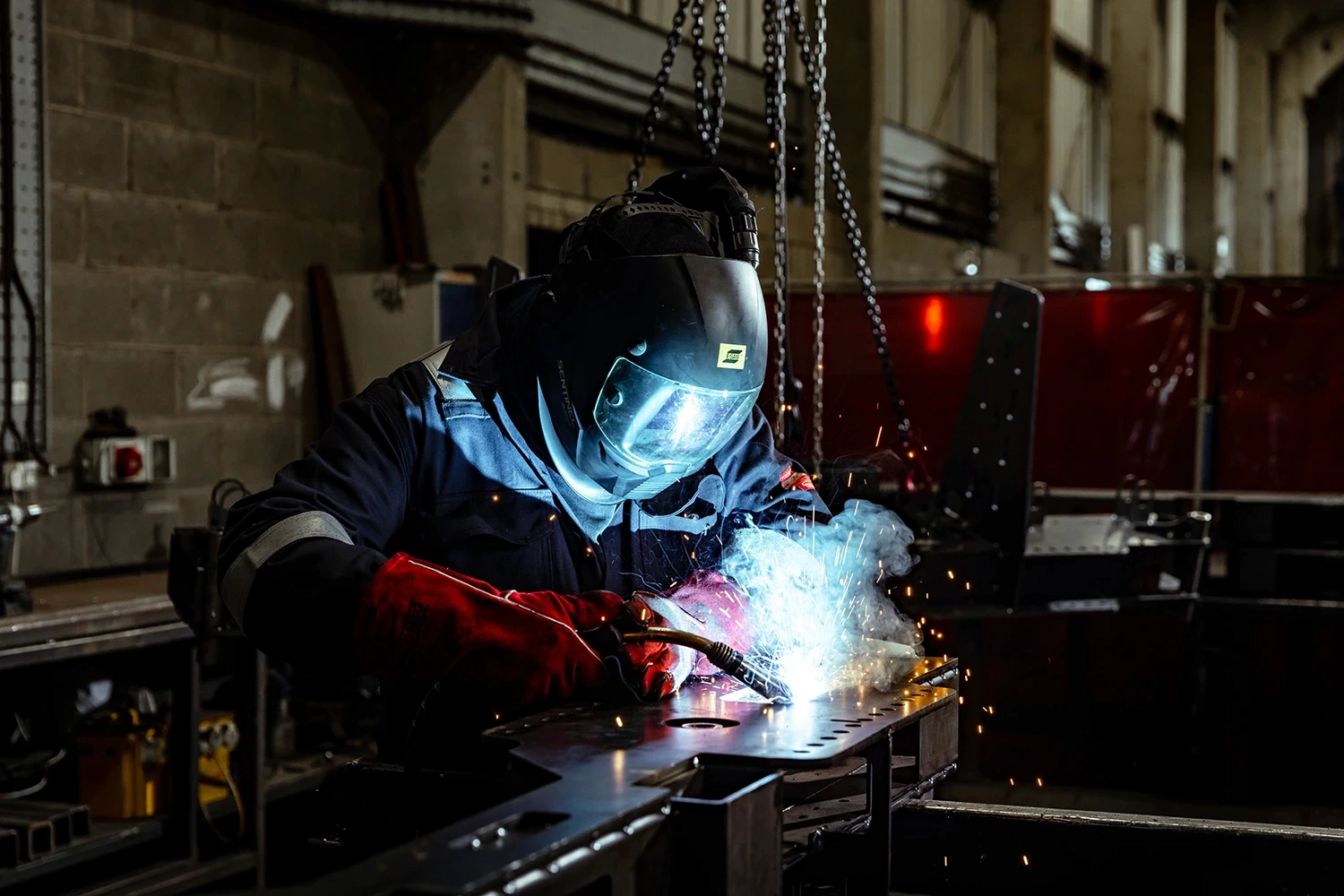 CASC engineer is full safety gear welding metal with sparks flying