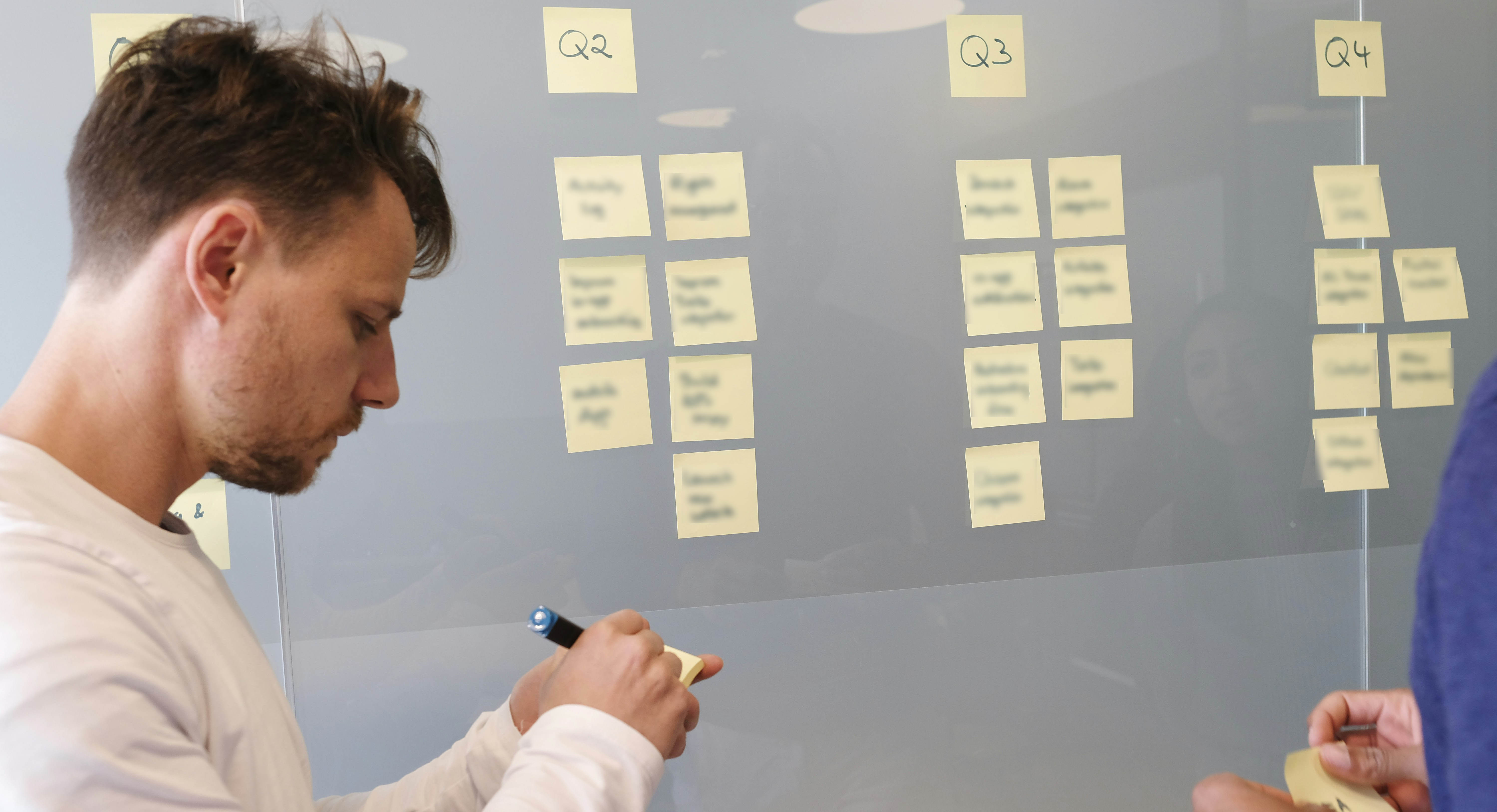 A man in a white lab coat working at a computer, viewing a 3D model on the screen in a laboratory or office setting.