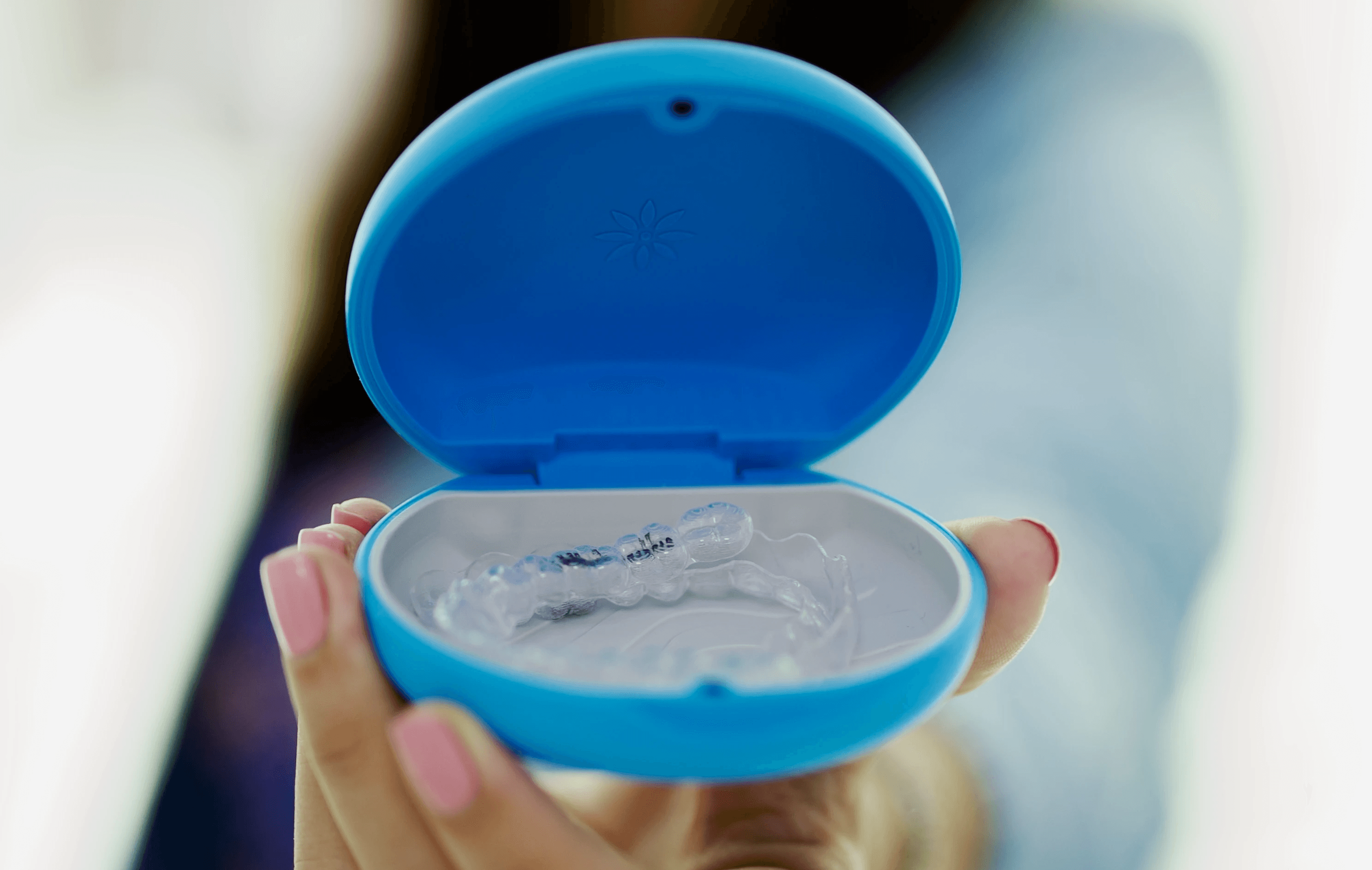 A woman holding and presenting an Invisalign® clear aligner in her hands.