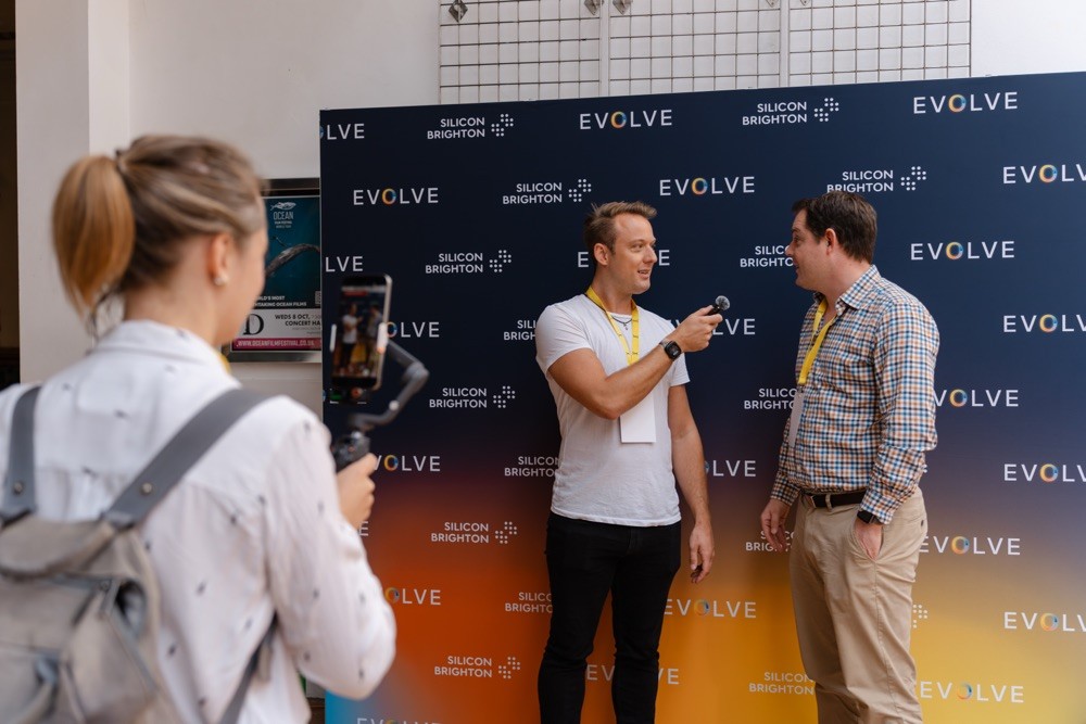 Attendee interview in front of Evolve and Silicon Brighton backdrop at Brighton tech event