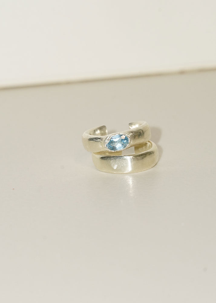 Silver ring with a blue gemstone on a light gray background