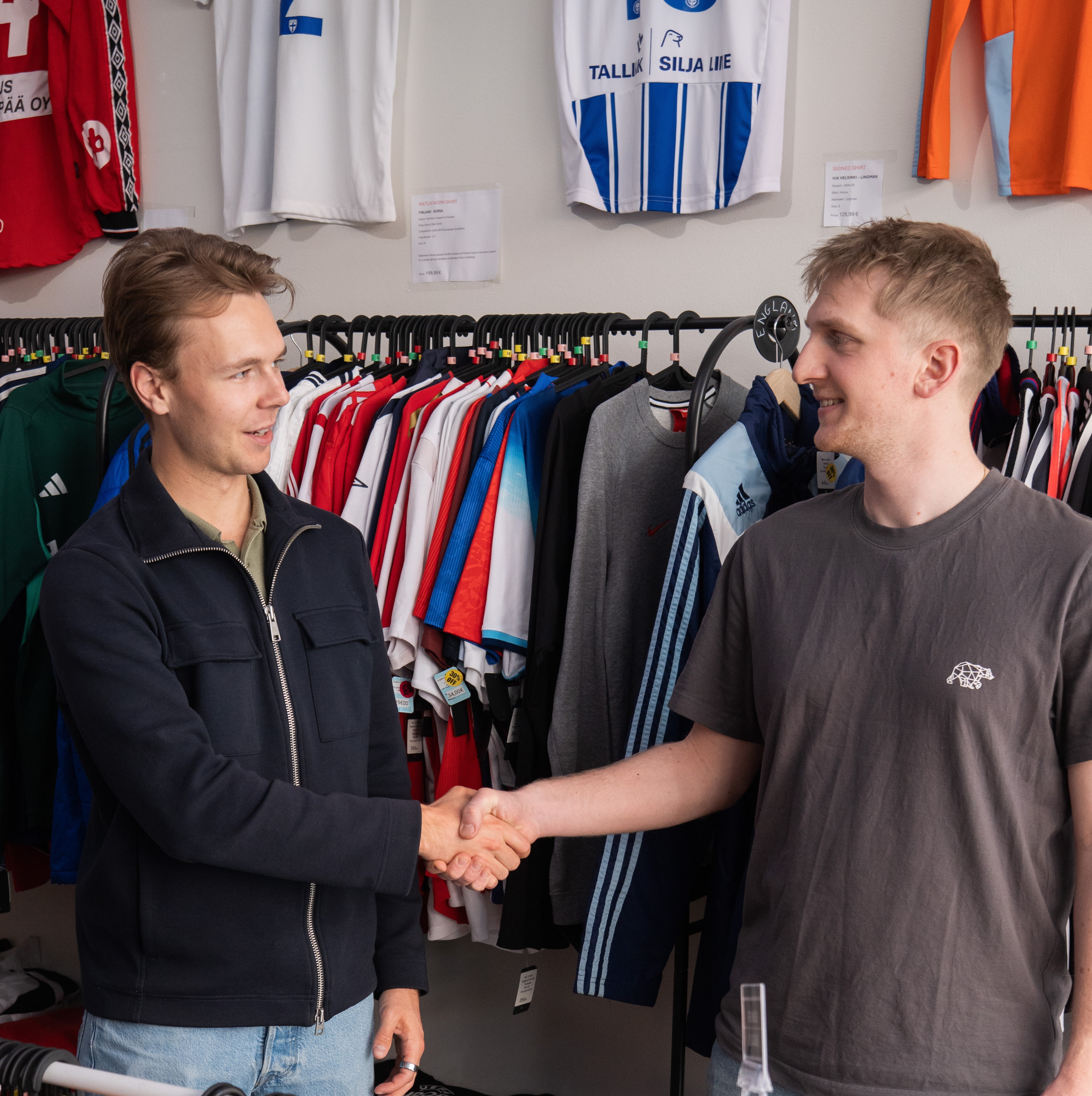 two men facing each other while shaking hands and smiling