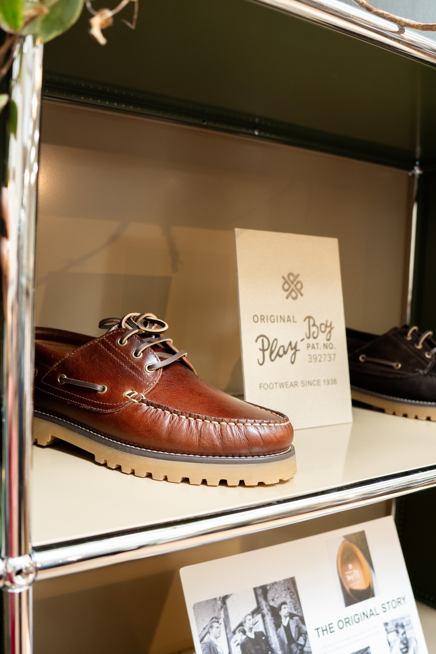 Une chaussure bateau sur une étagère à côté d'une PLV de la marque Playboy shoes