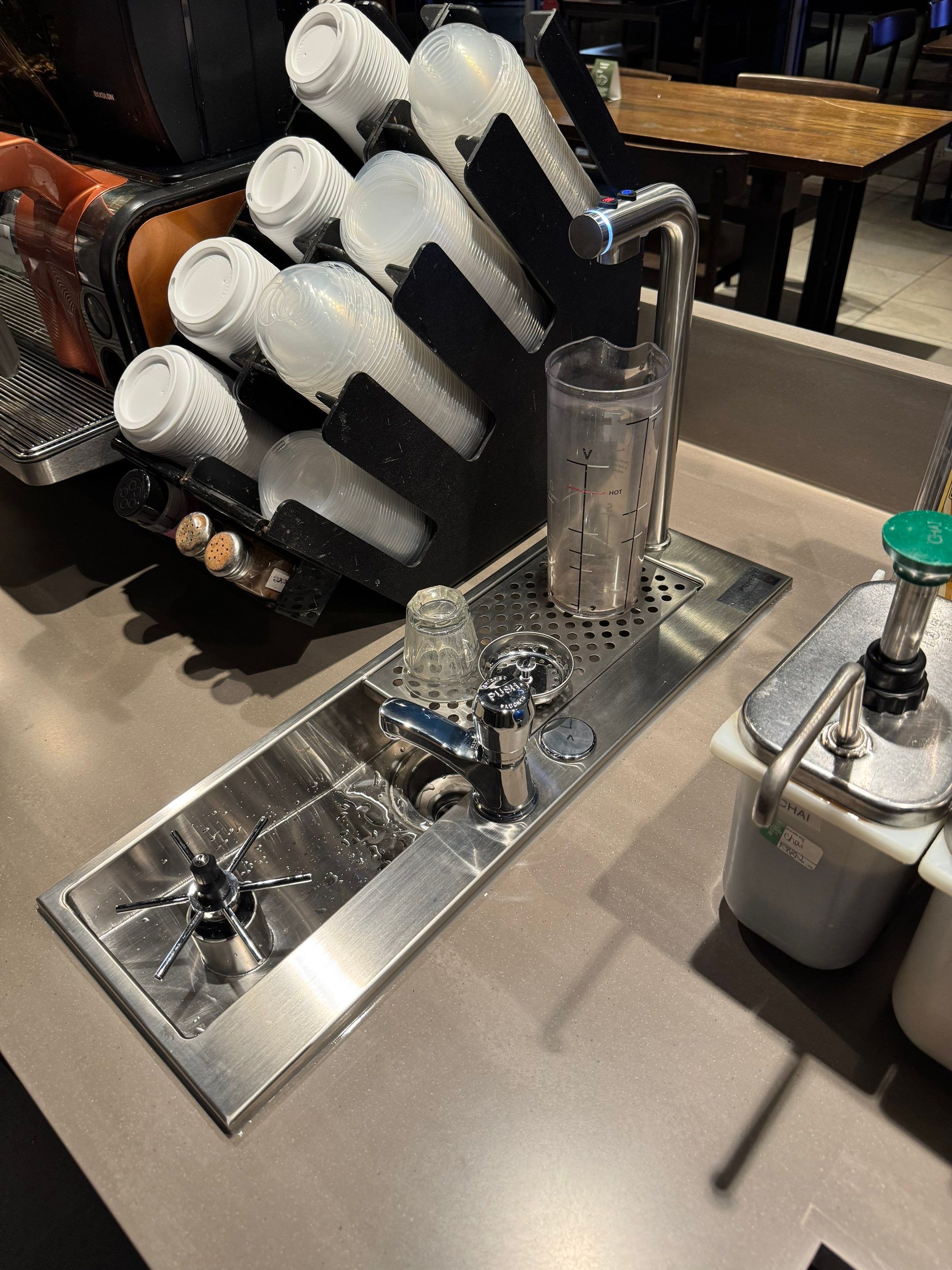 Close-up of new Starbucks countertop installation with integrated rinse sink, hot water tap, and cup station, showing clean alignment and polished finish.