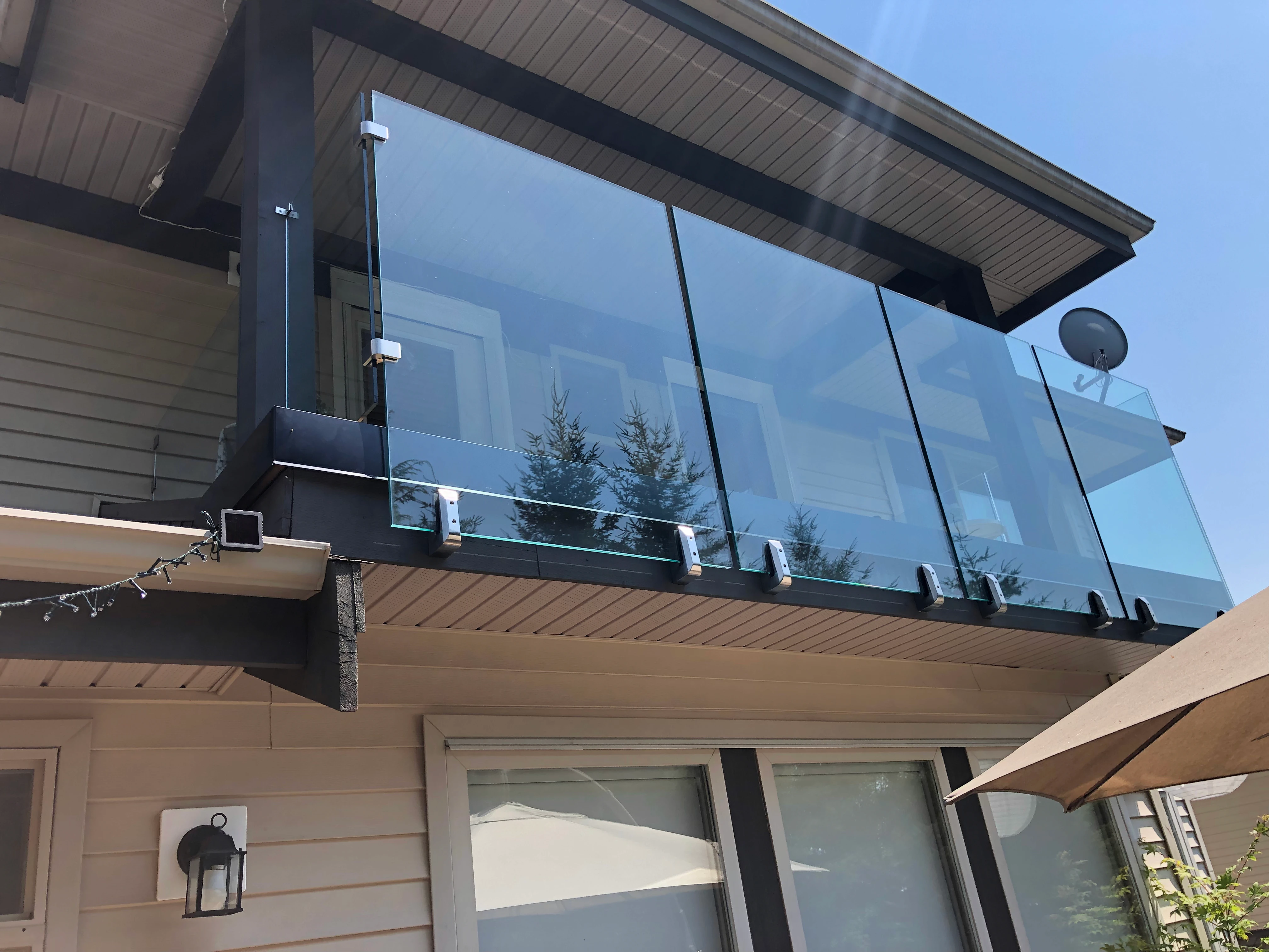 Spigot glass railing on a second storey balcony with clear glass panels held by fascia mounted stainless spigots.