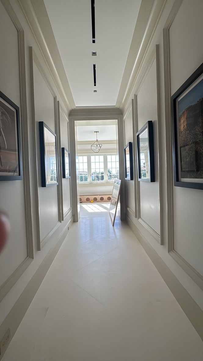 Hallway gallery wall of framed photography leading to a sunlit window nook