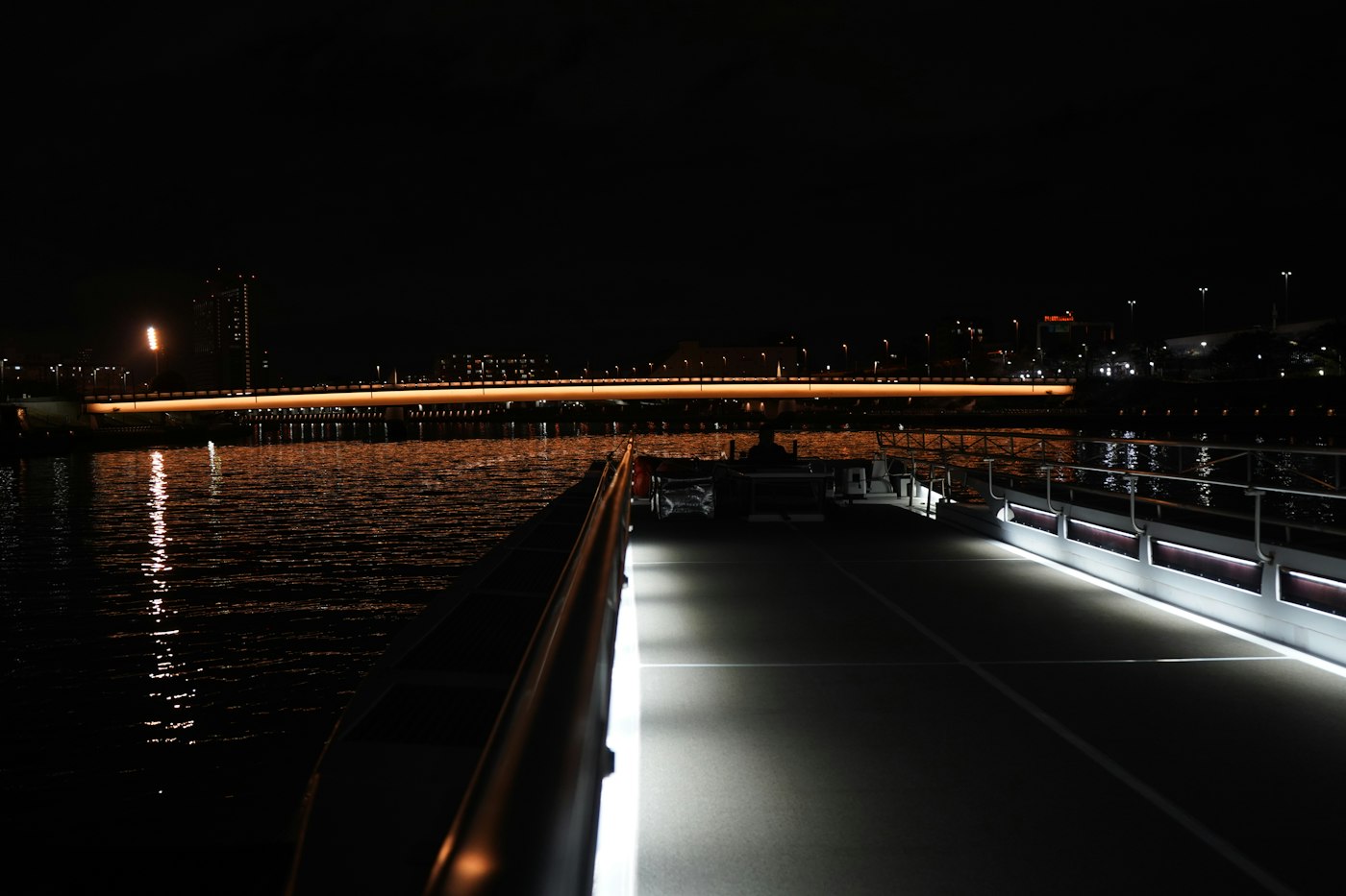 The lit rail of an empty deck at night