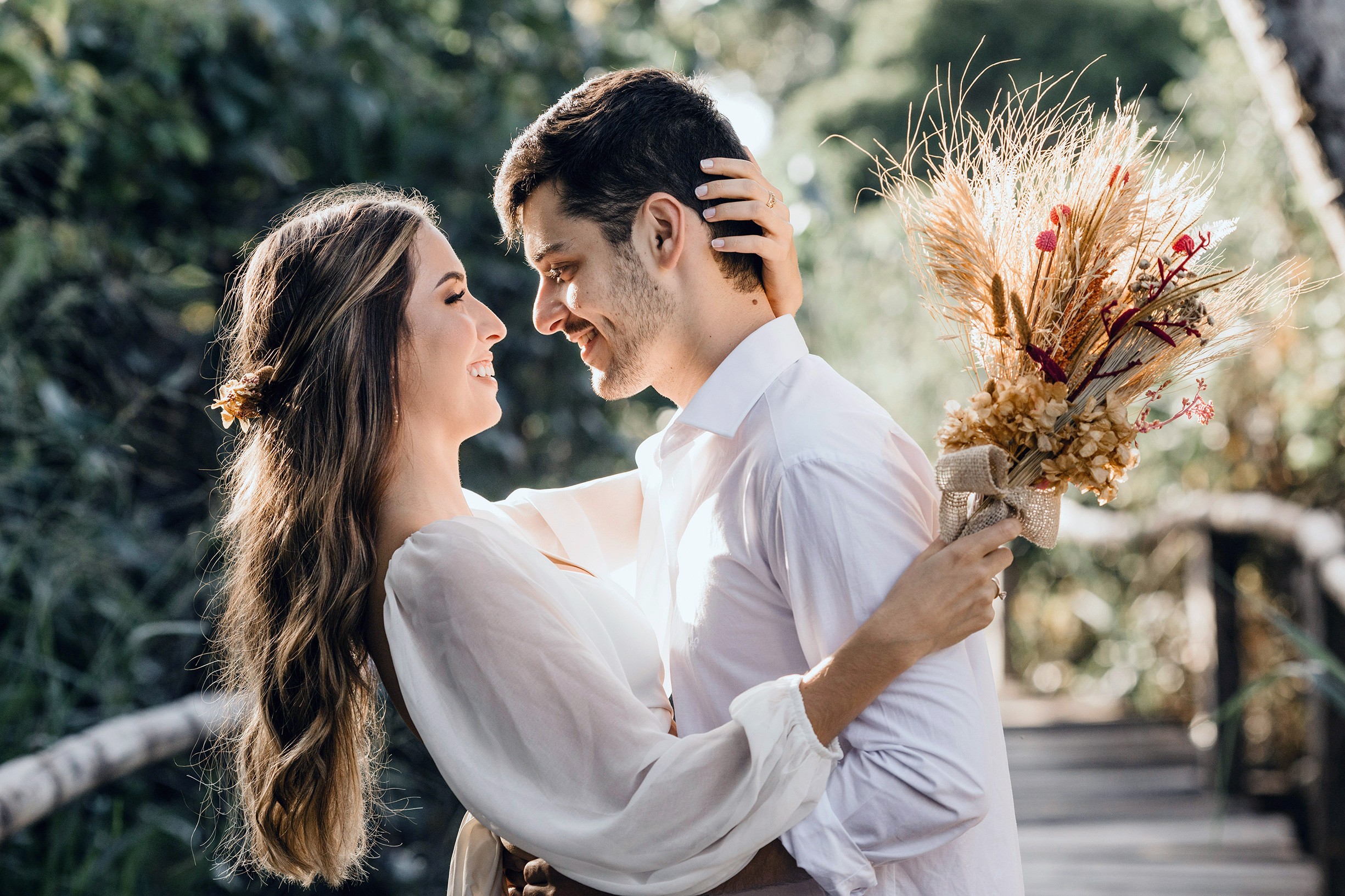 A couple embraces lovingly on a rustic wooden bridge.