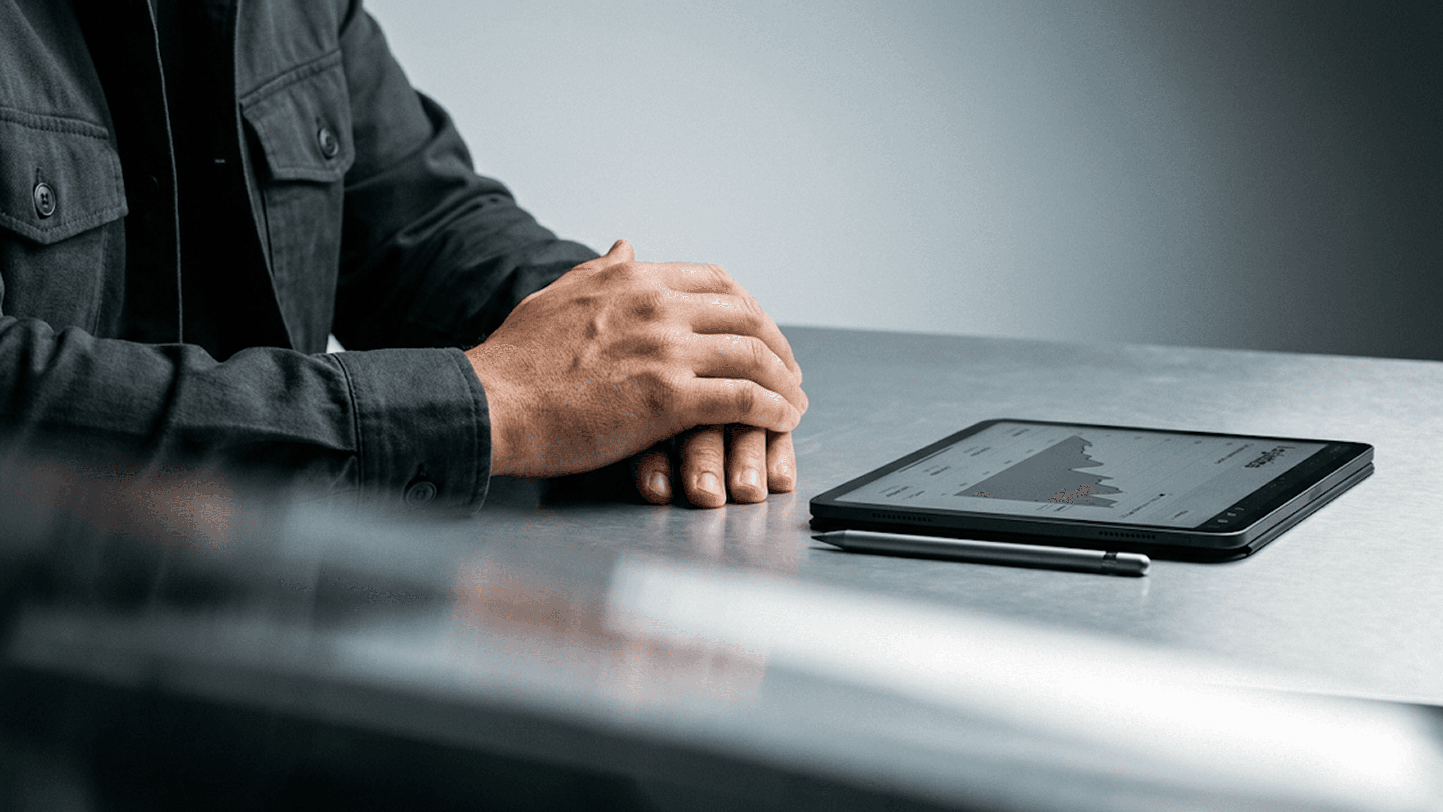 Professional analyzing data on a tablet at a desk.