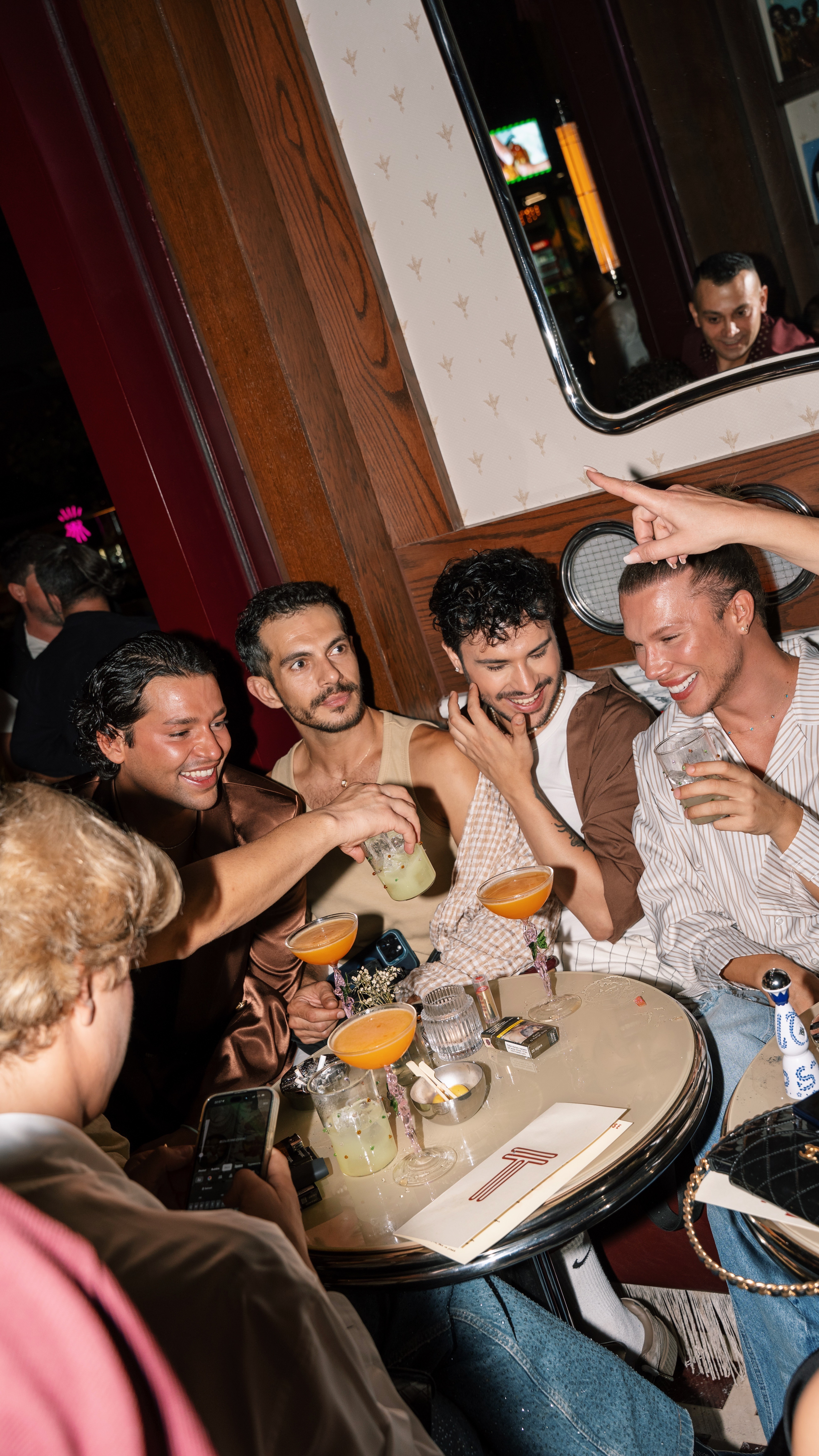 Wooden sauna cabin and hot tub set among rocky mountains and greenery under clear sky.