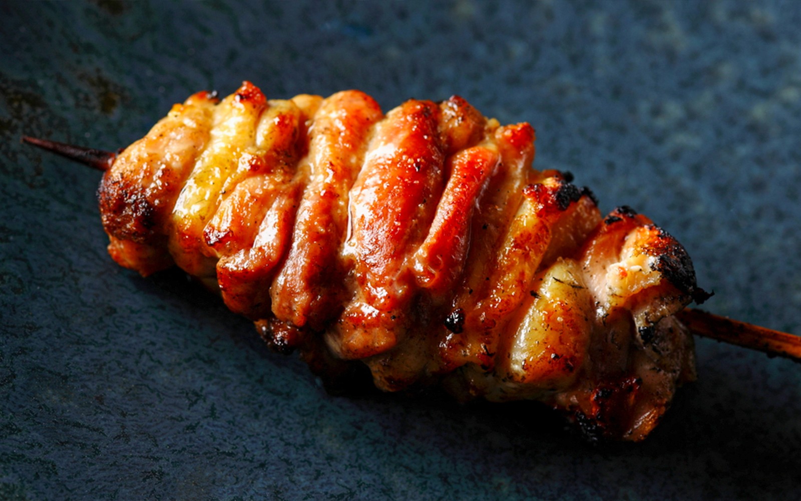 Yakitori chef grilling skewers at Yakitori Tsukiya in Tokyo for 6/9-course meal experience.