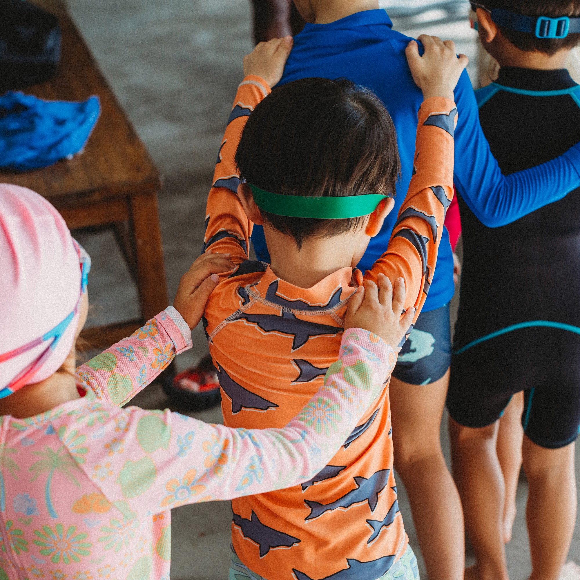Children lining up with hands on each other's shoulders before a session at a Swish holiday swim camp