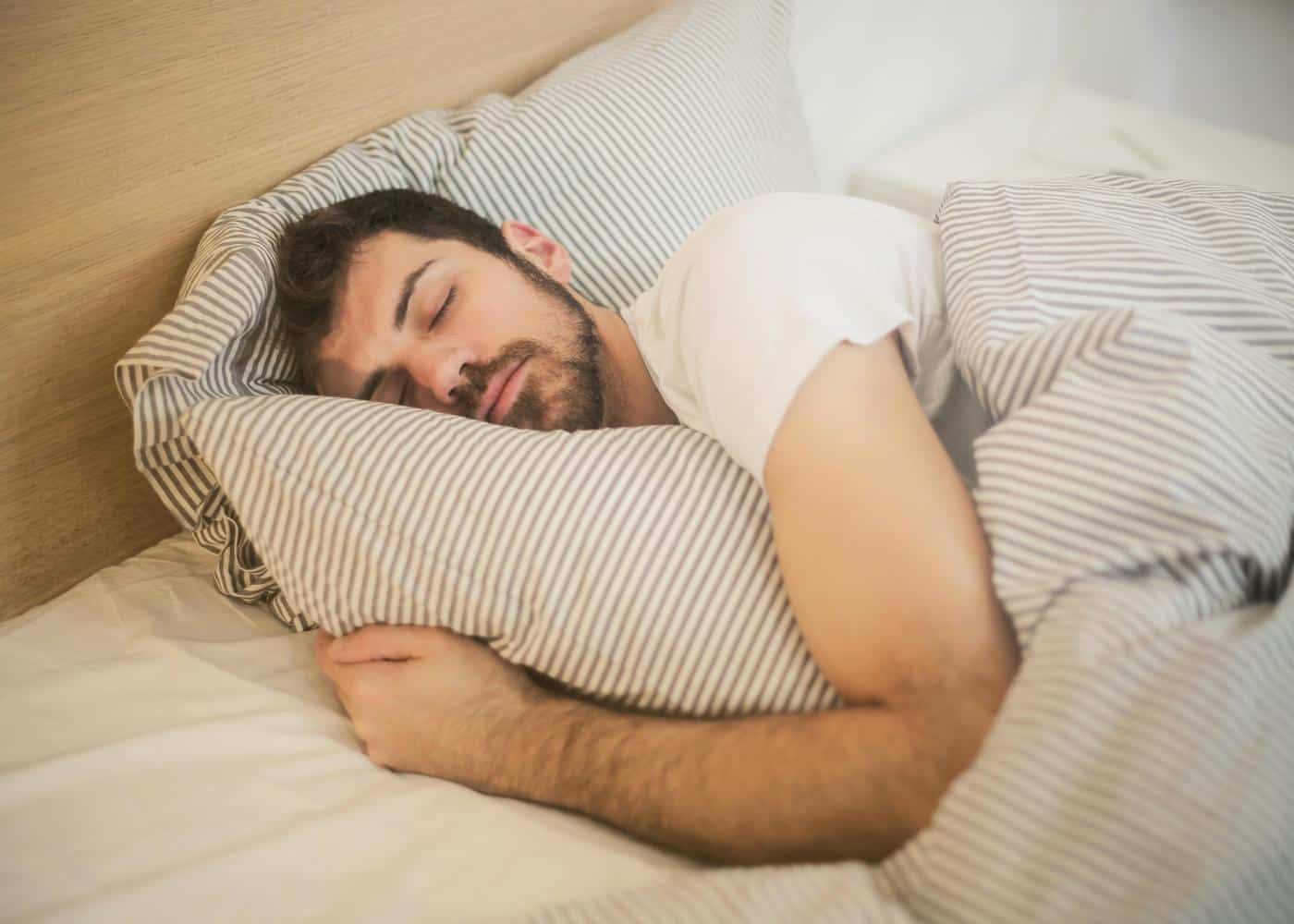 Man sleeping on a bed hugging a pillow
