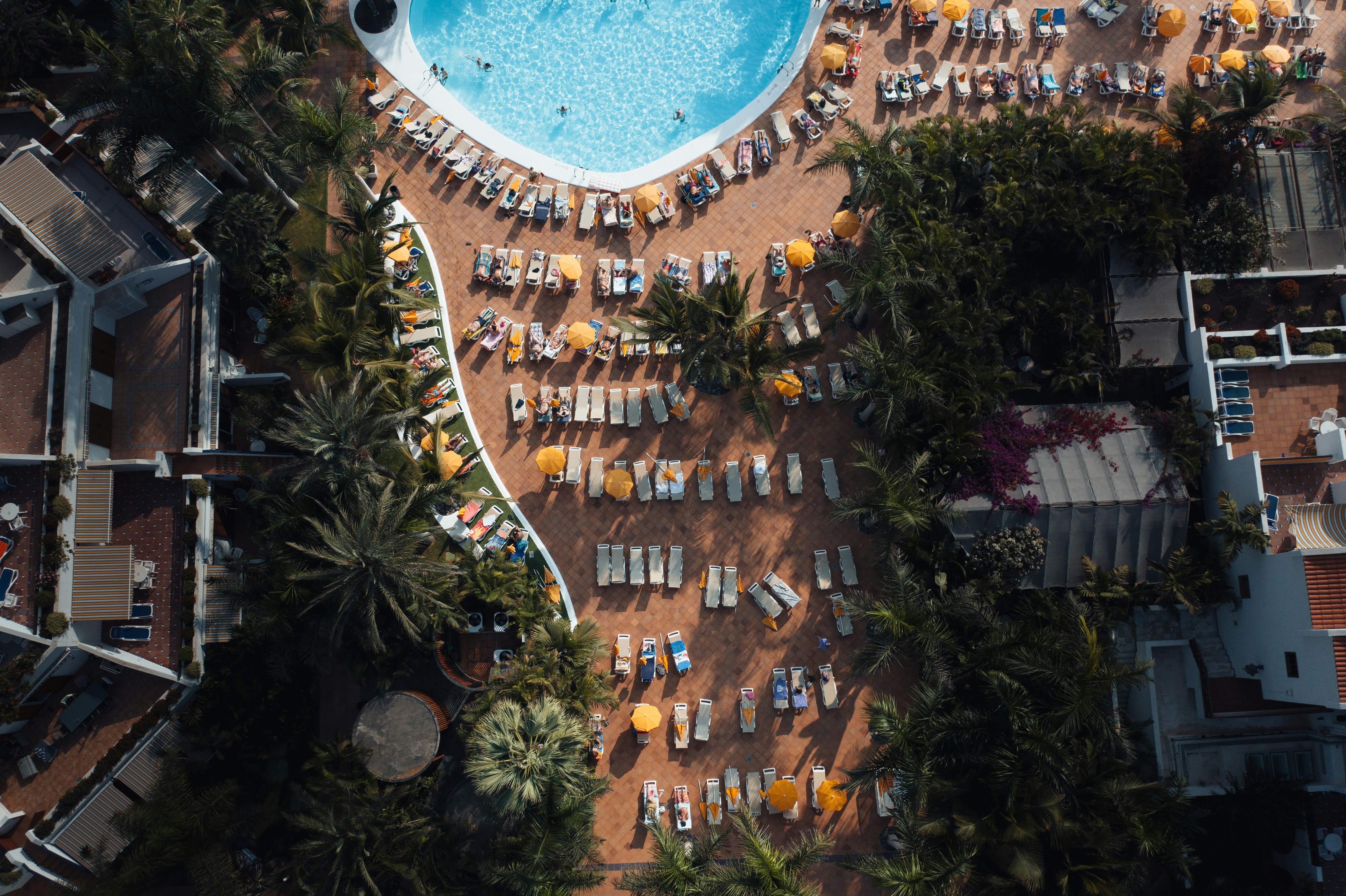 an aerial view of a resort pool with chairs and umbrellas