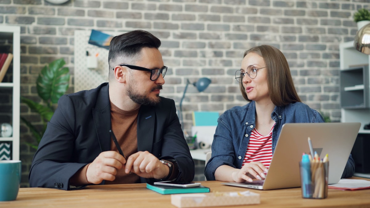 Travel agent and client reviewing planning fees on a laptop at an office desk