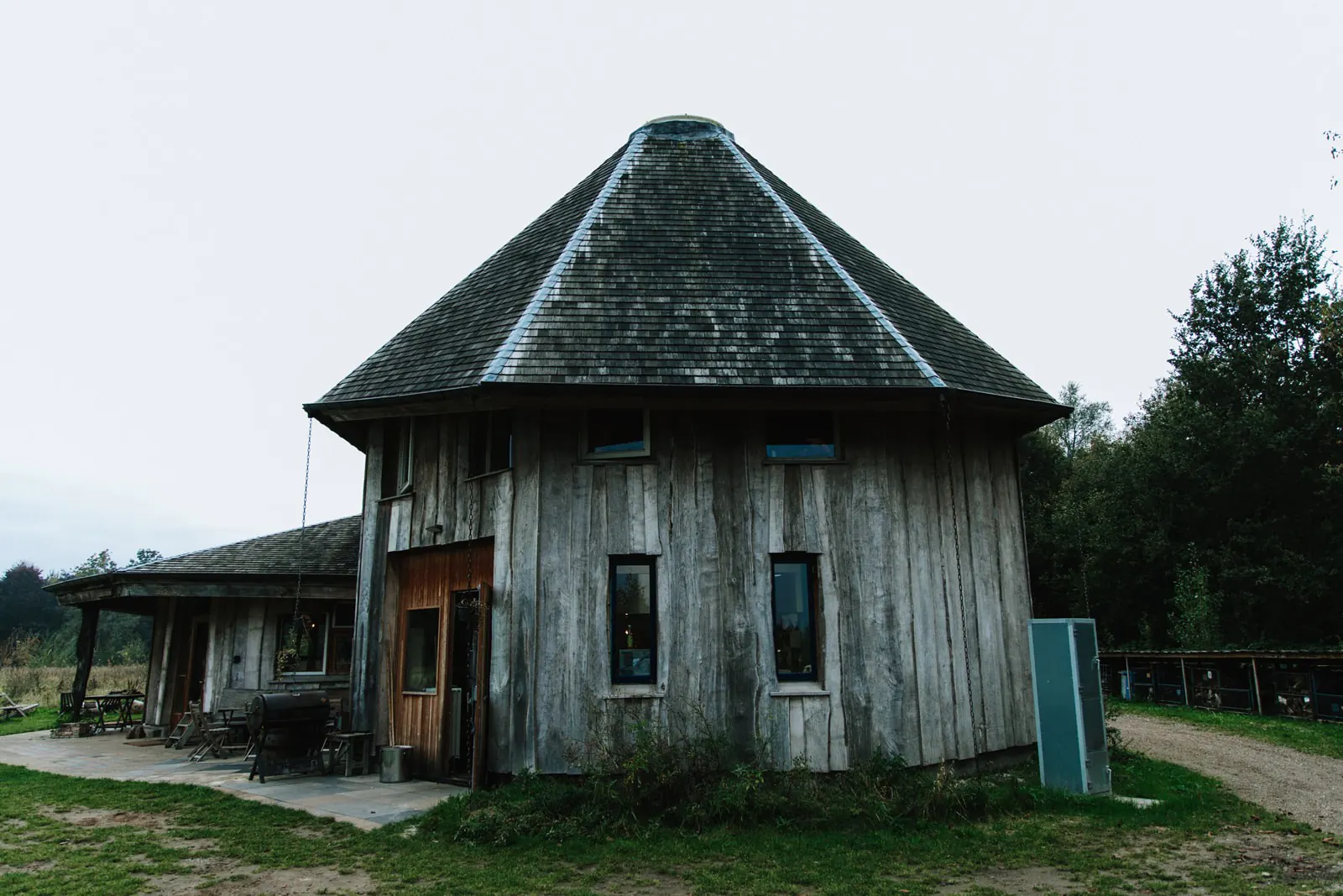 Achthoekig houten gebouw met een puntdak in een groene omgeving