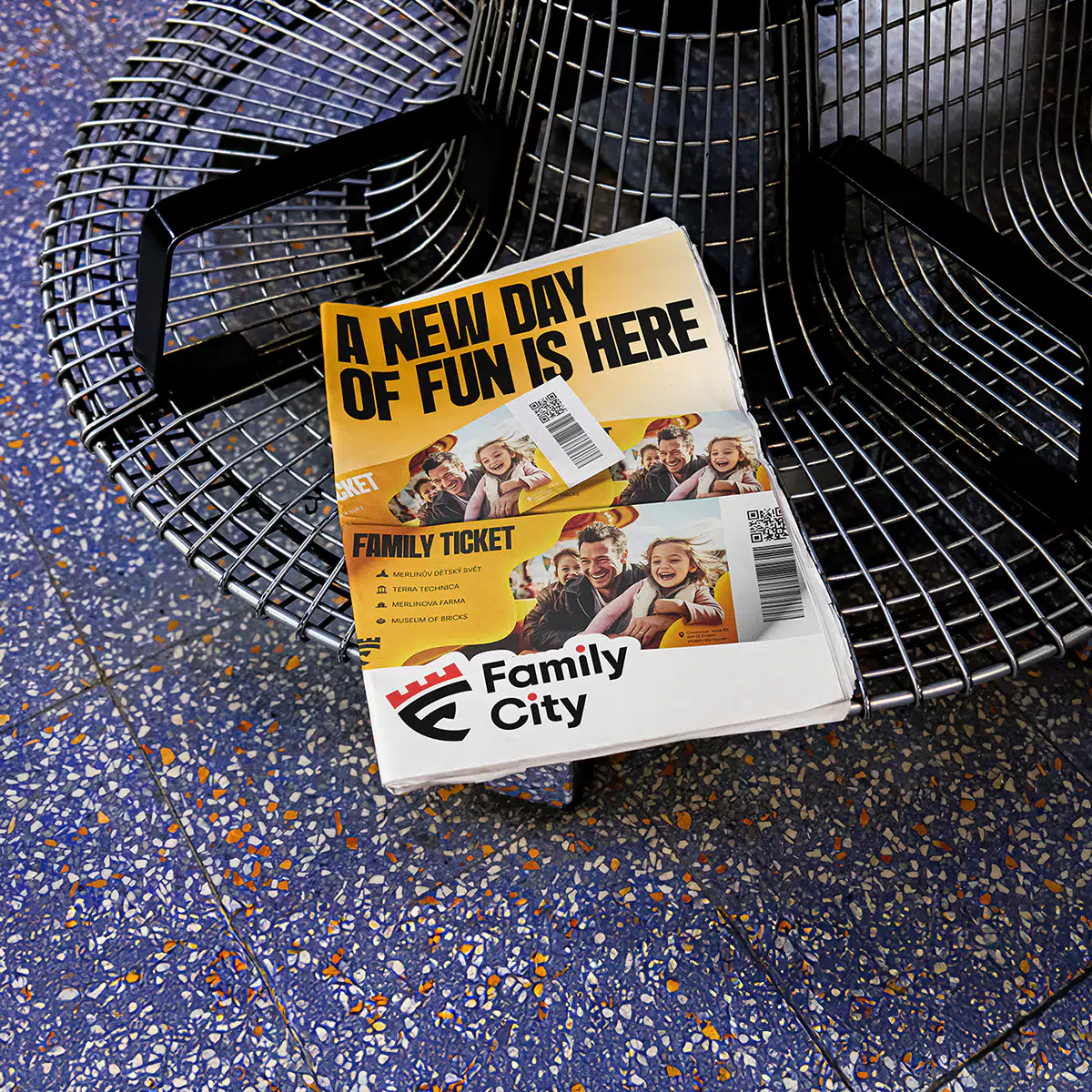 A Family City promotional newspaper with a bright yellow cover and family-themed imagery placed on a metal bench.