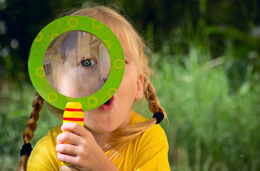 Young girl in garden with a magnifying glass