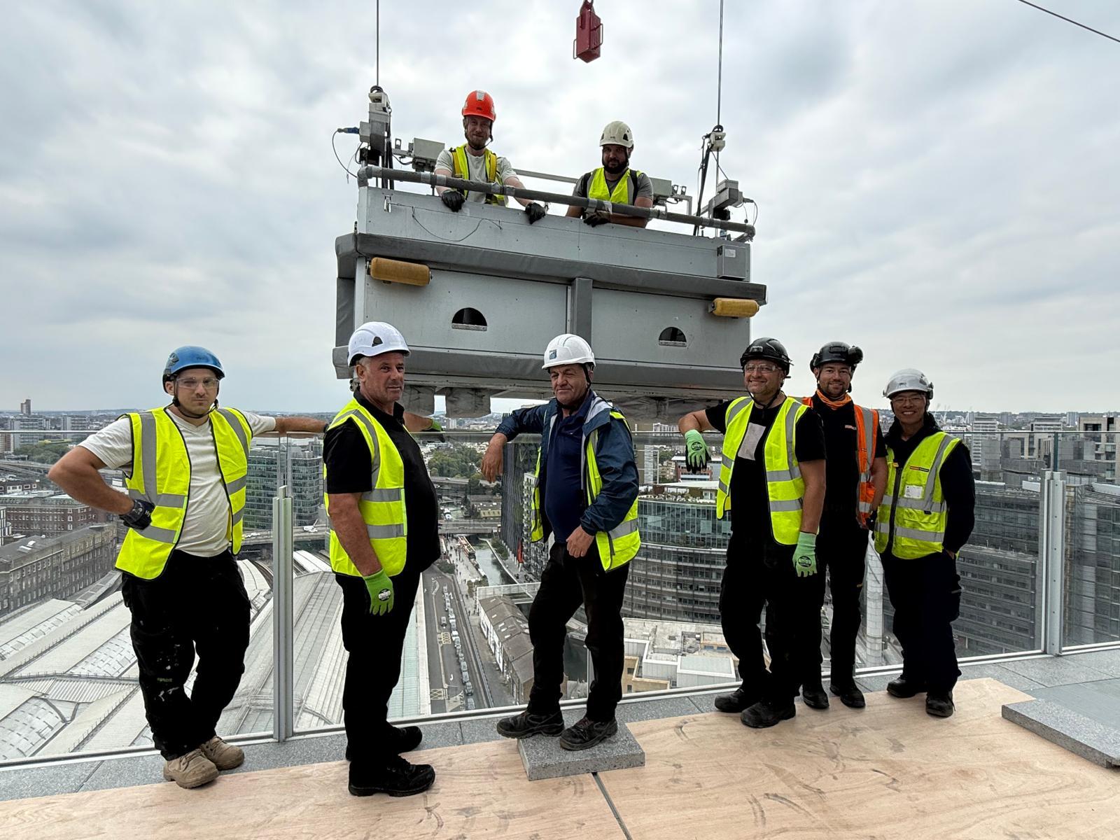 The Façade Doctor team on a rooftop high above London, beside a building maintenance cradle