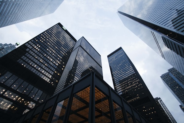 Looking up at a cluster of downtown high-rise office towers against a bright sky