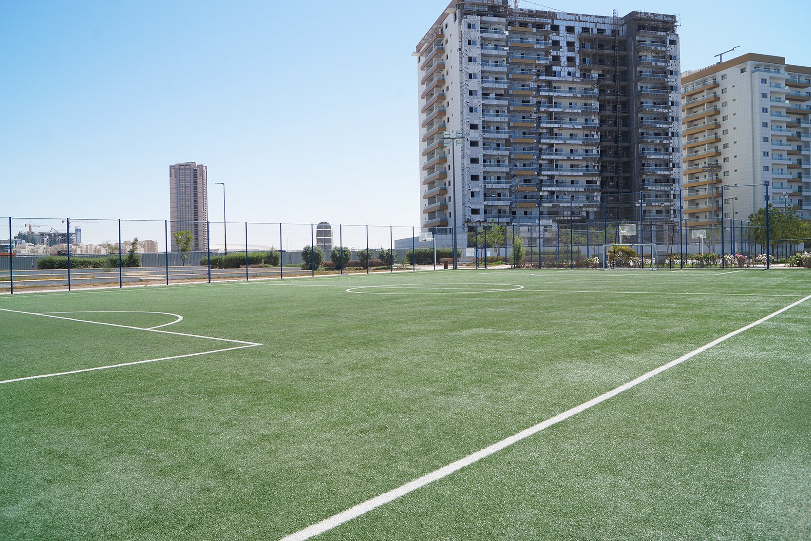 Professional football turf field with residential towers in the background. Premium Living Legends amenities.