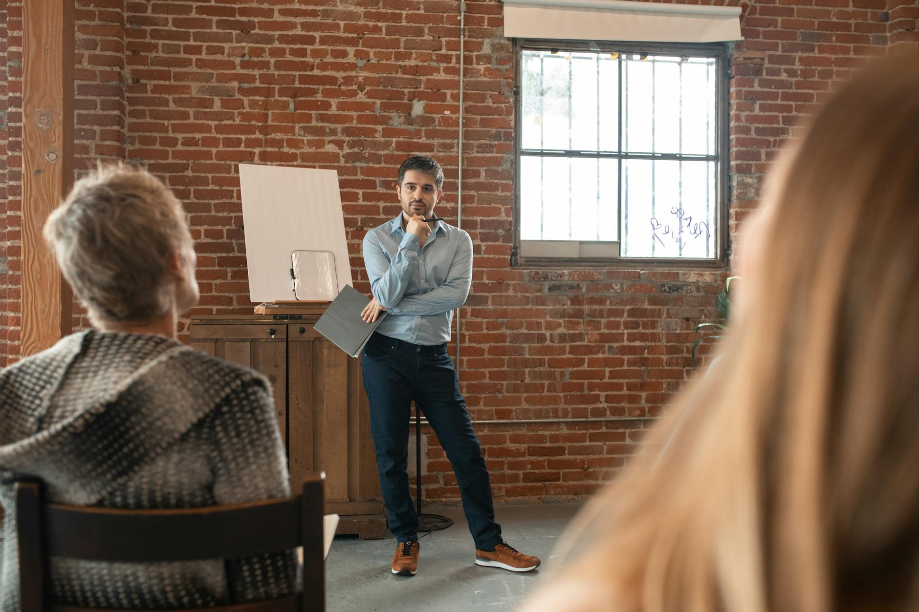A teacher holds a digital tablet and uses a rubric to discreetly observe students practicing woodworking techniques.