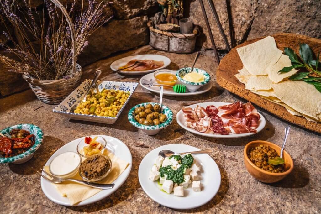 A shared Sardinian meal with pasta and wine