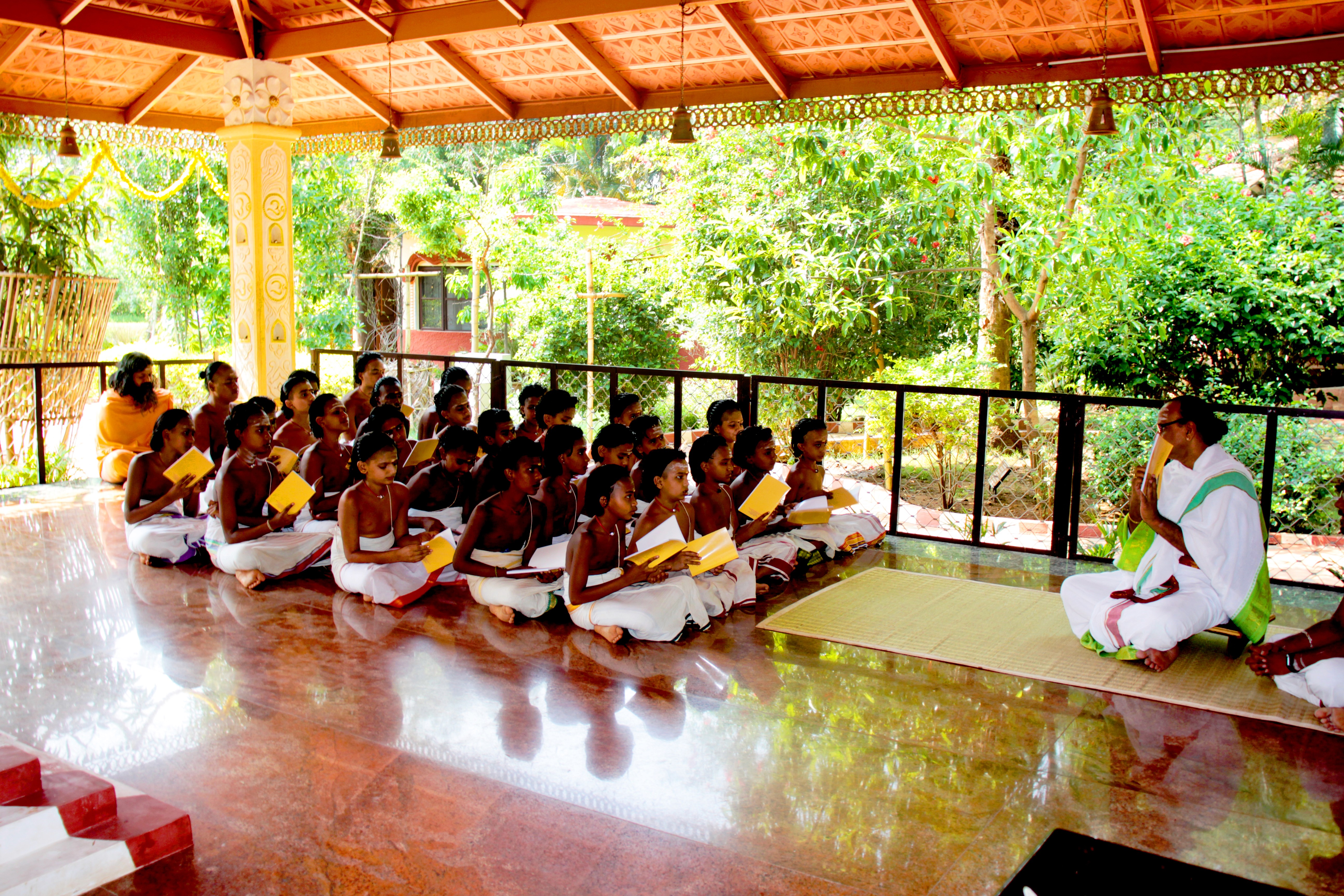 A winding road cuts through rocky terrain, surrounded by patches of green grass and illuminated by sunlight.