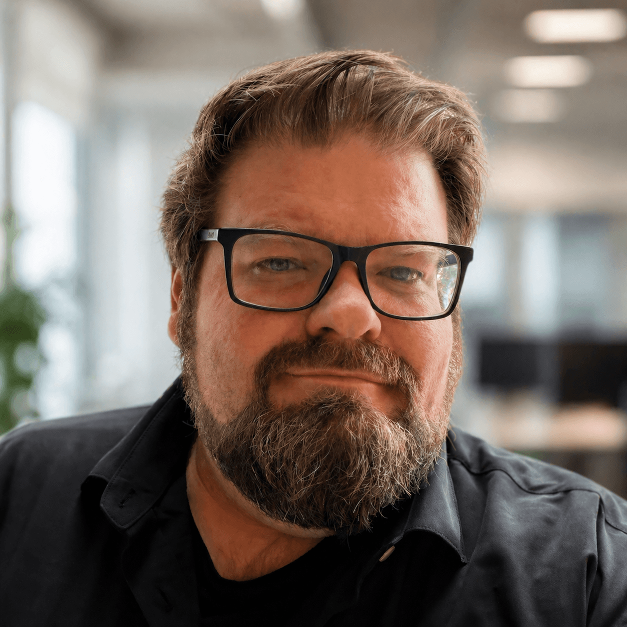 Portrait of Brian Talbot- He has black framed glasses and a short beard.