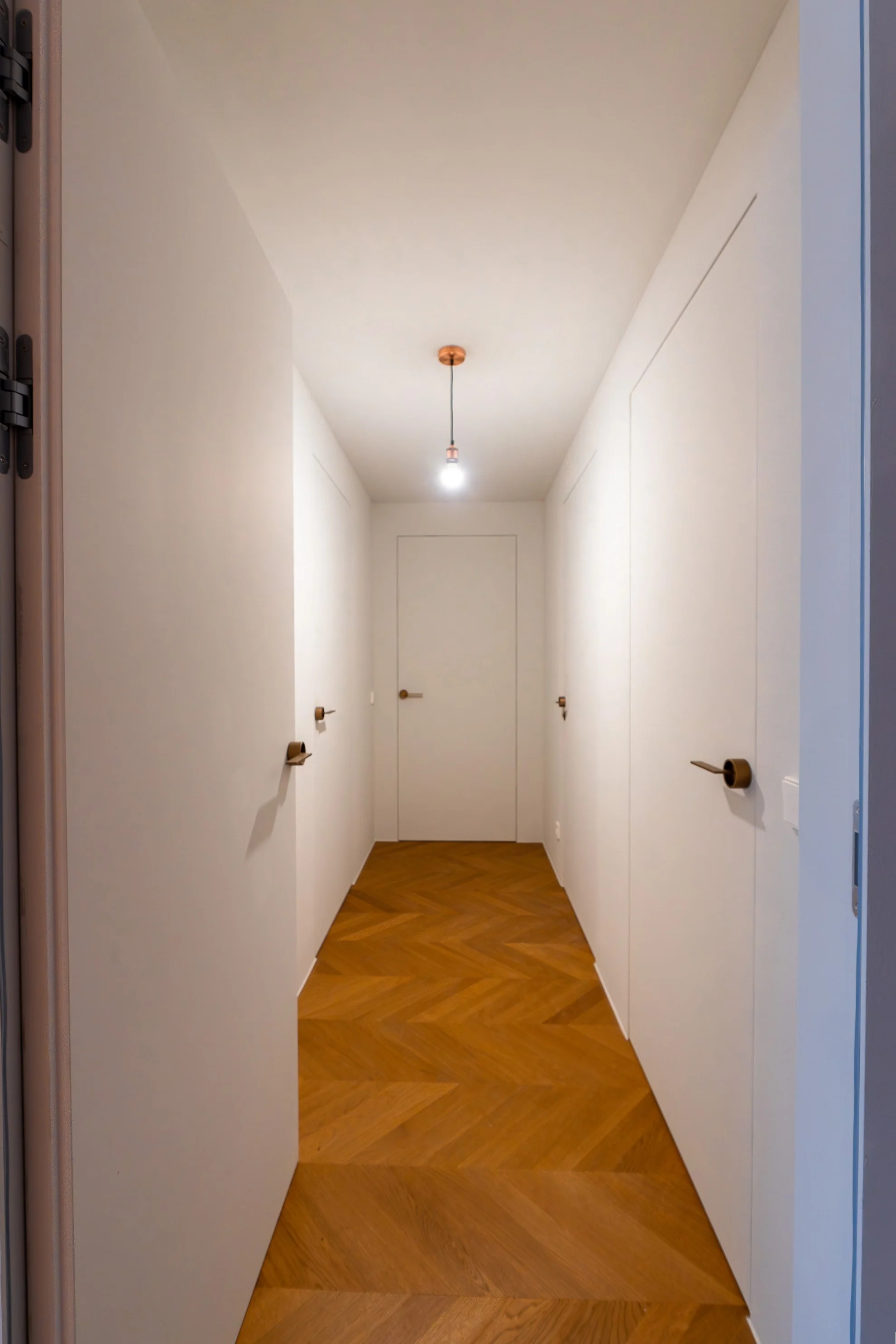 Heller Flur mit frisch verlegtem Chevron-Parkettboden in warmem Holzton