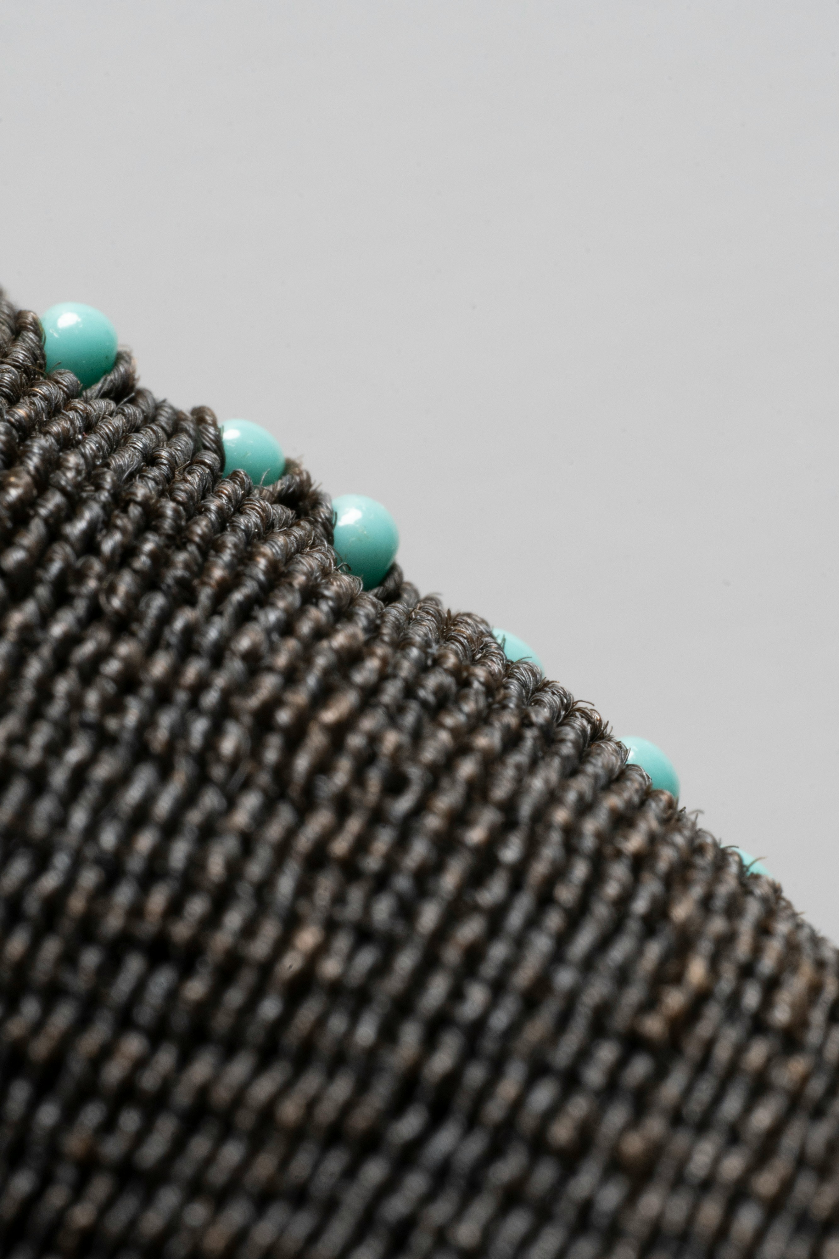 Close-up of dark woven fabric with turquoise beads