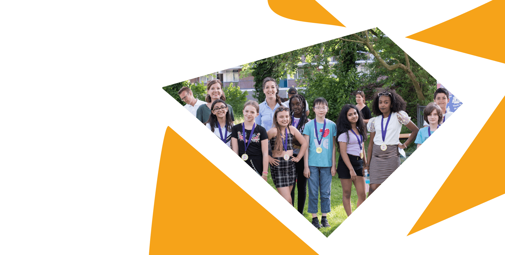 Groep kinderen met medailles poseert samen met begeleiders buiten in het gras