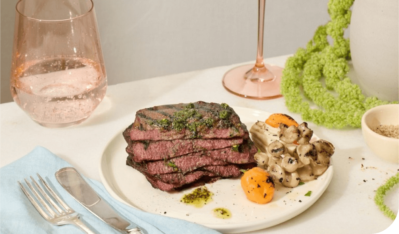 A plate of grilled steak, vegetables, and a glass of wine.