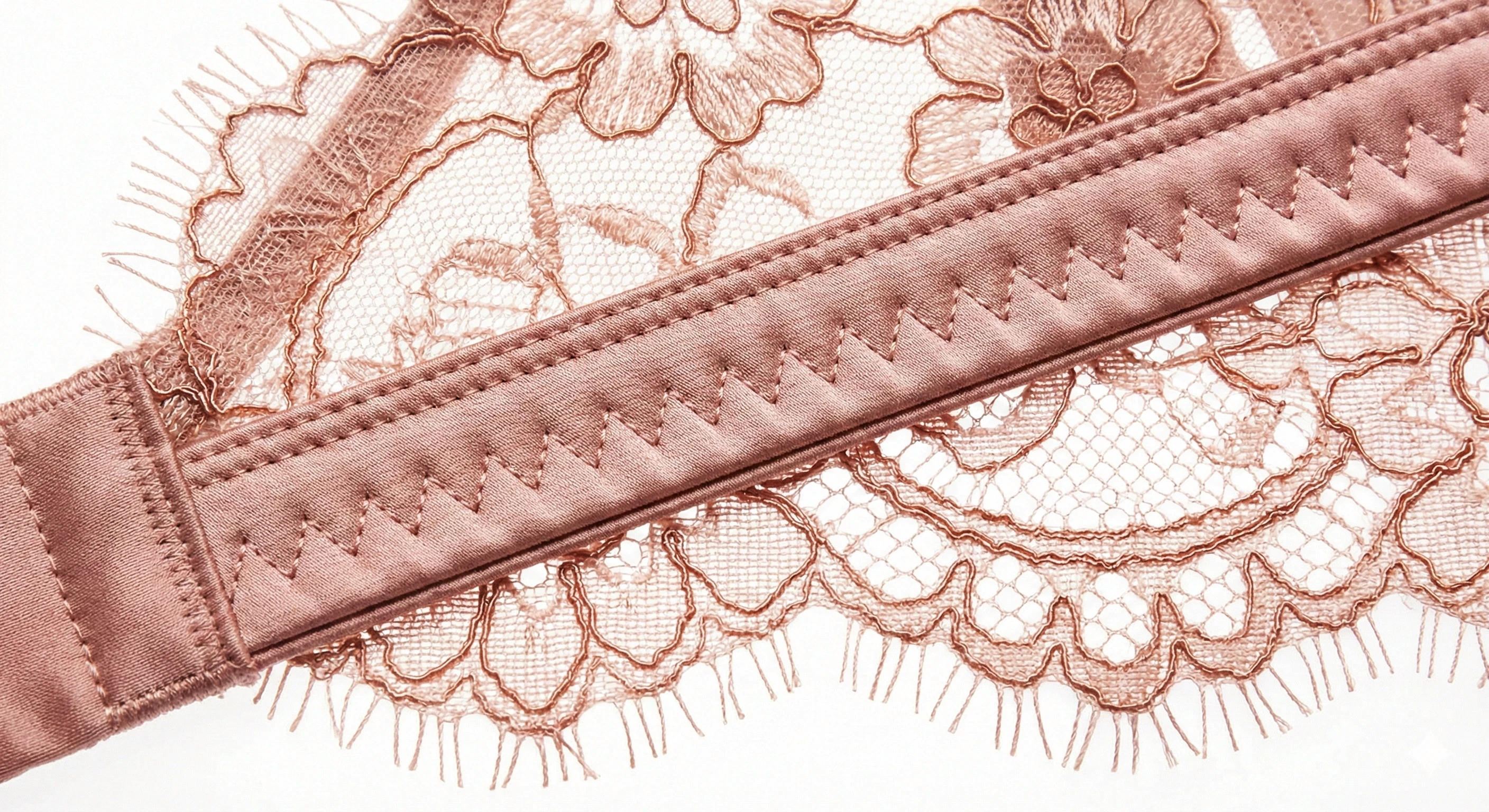 Blush lace lingerie detail with satin trim and fine stitching.