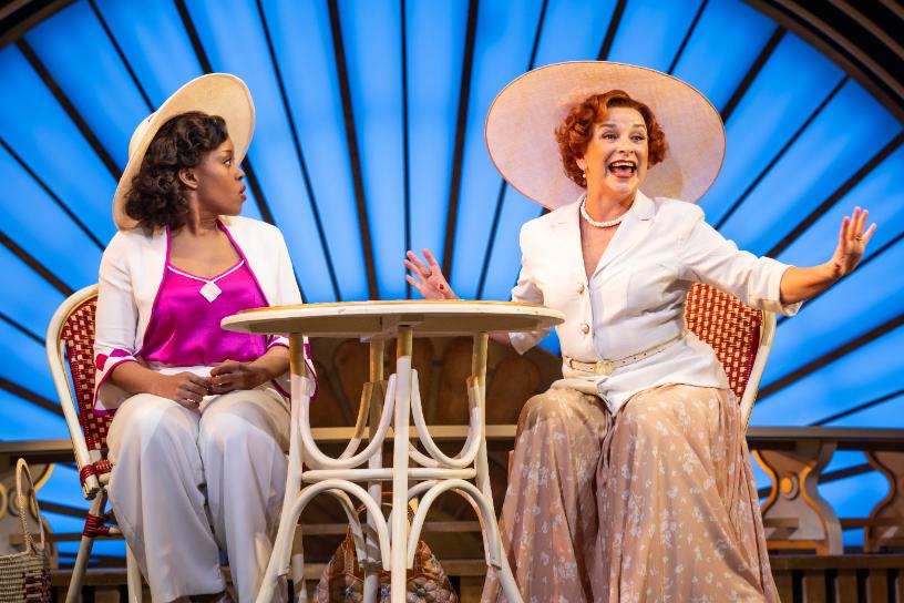 op Hat scene with two women chatting in bright Art Deco surroundings.