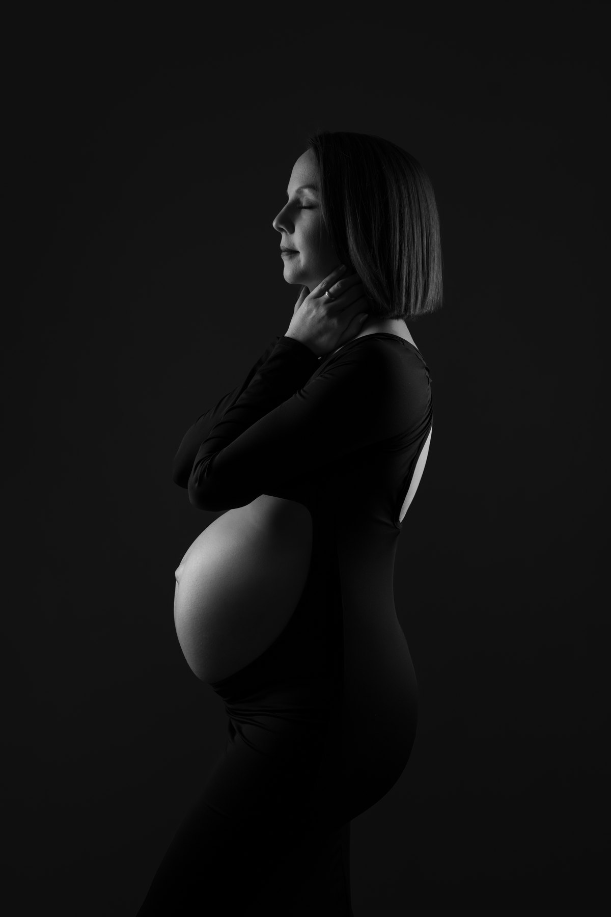 Schwangere als Silhouette vor dunklem Grund