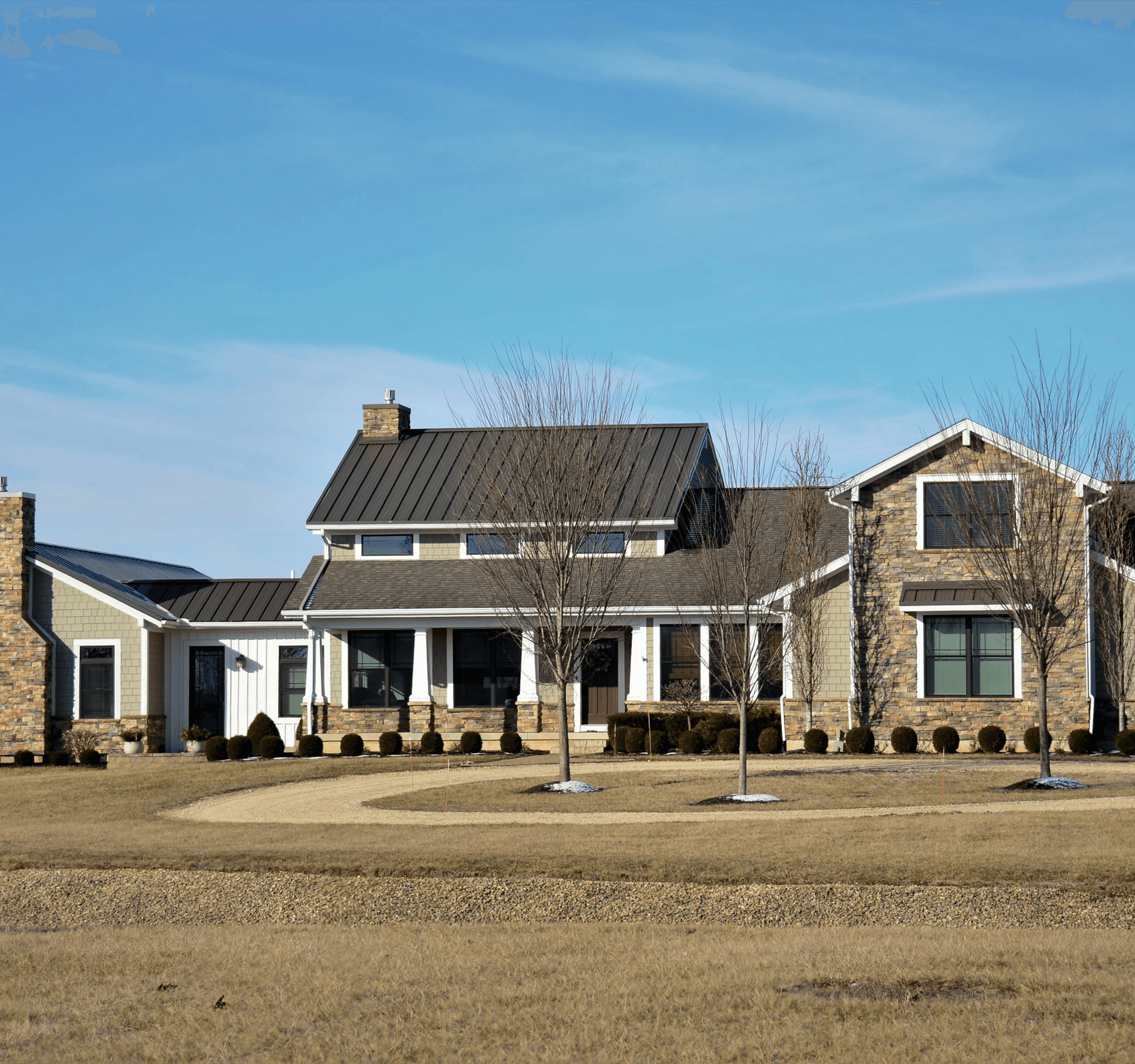 A modern house with a large lawn and a partly cloudy sky.