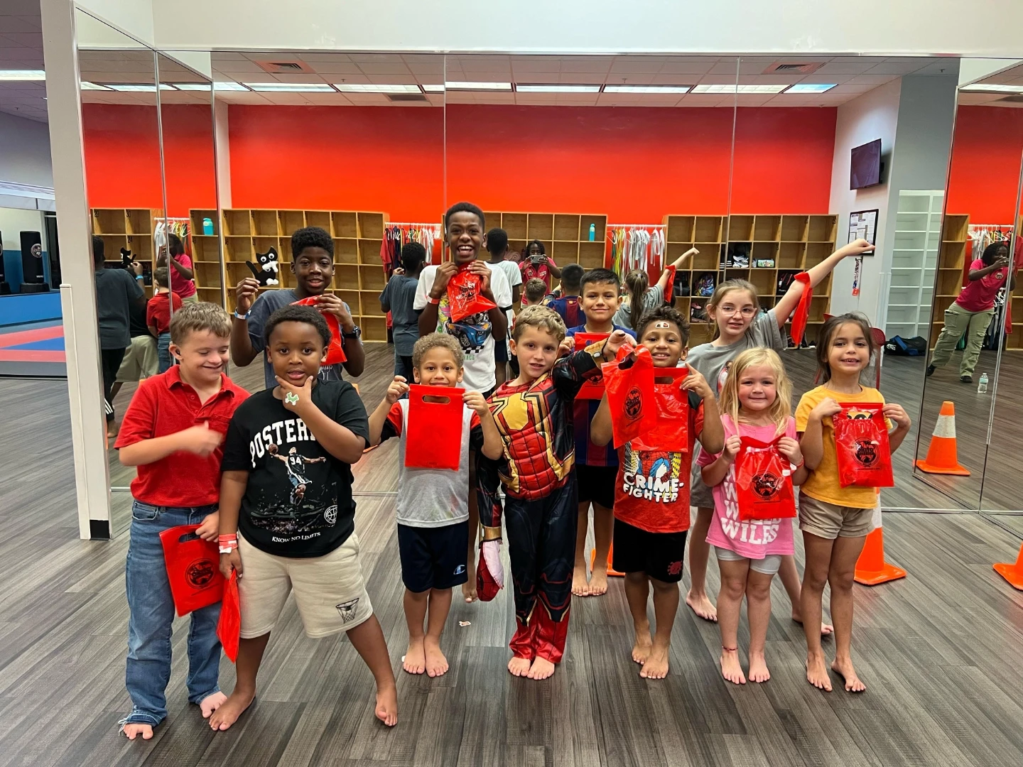 Group of children smiling at the camera while holding goodie bags at a Parent's Night Out event.