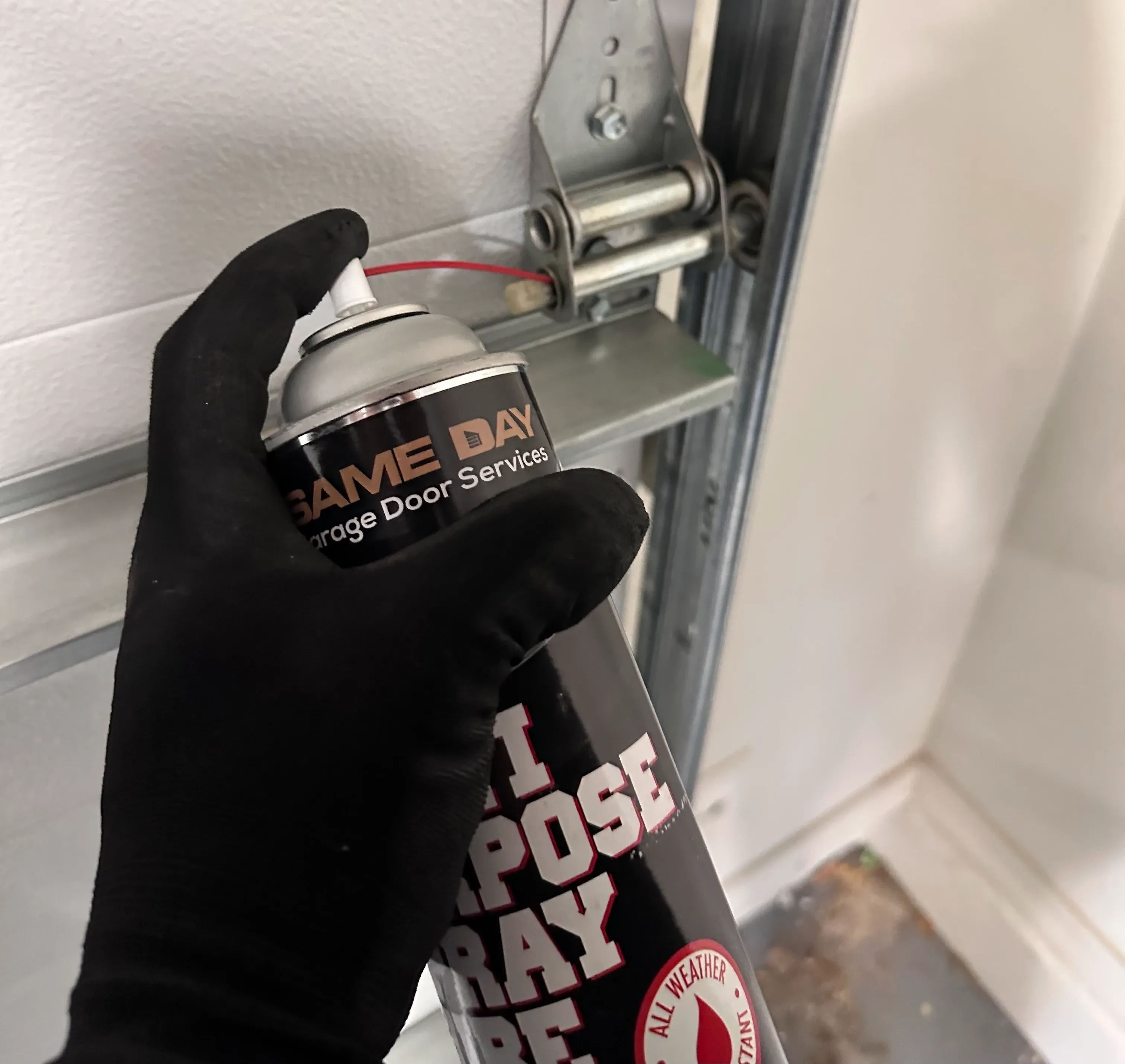 close up photo of a same day garage door services technician's hand hold a lubricating spray