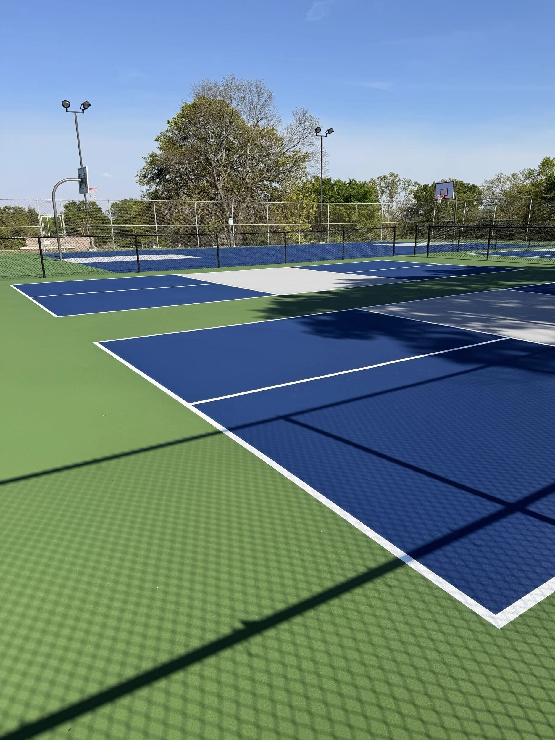 Multiple resurfaced pickleball courts with navy and gray color system at Bell Park in Greenwood, AR