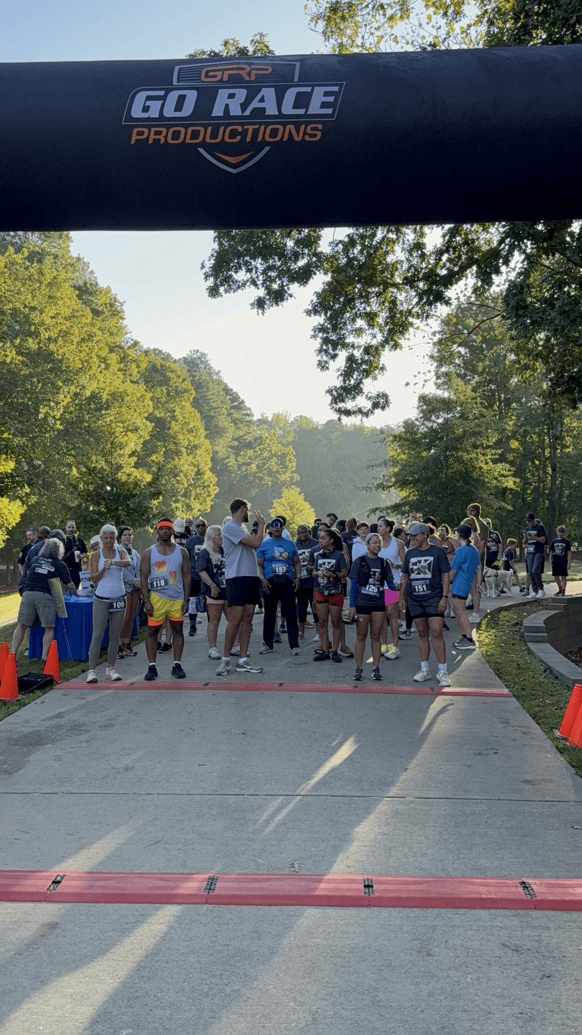 Runners lined up at the starting line of a Go Race Productions event. Spectators cheering as the race begins.