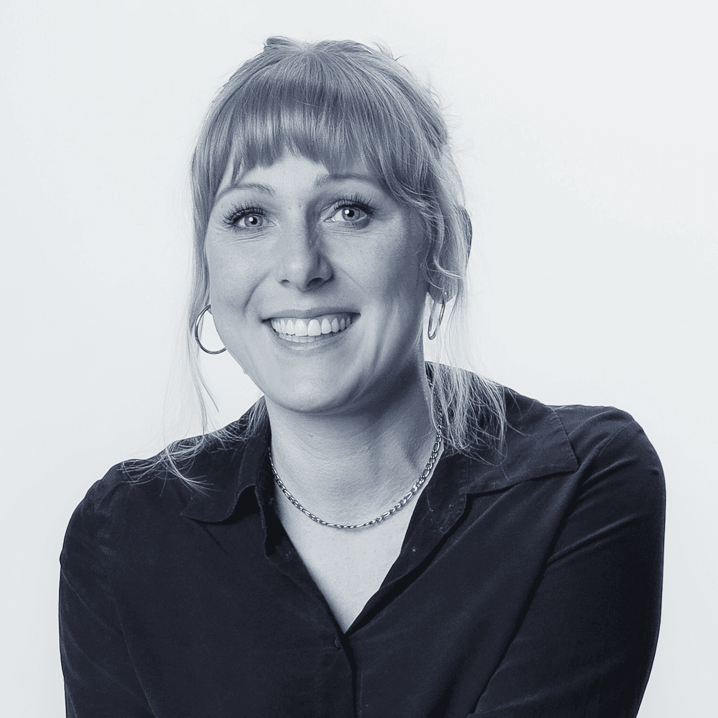 Portrait of a laughing person with curly hair wearing a white shirt