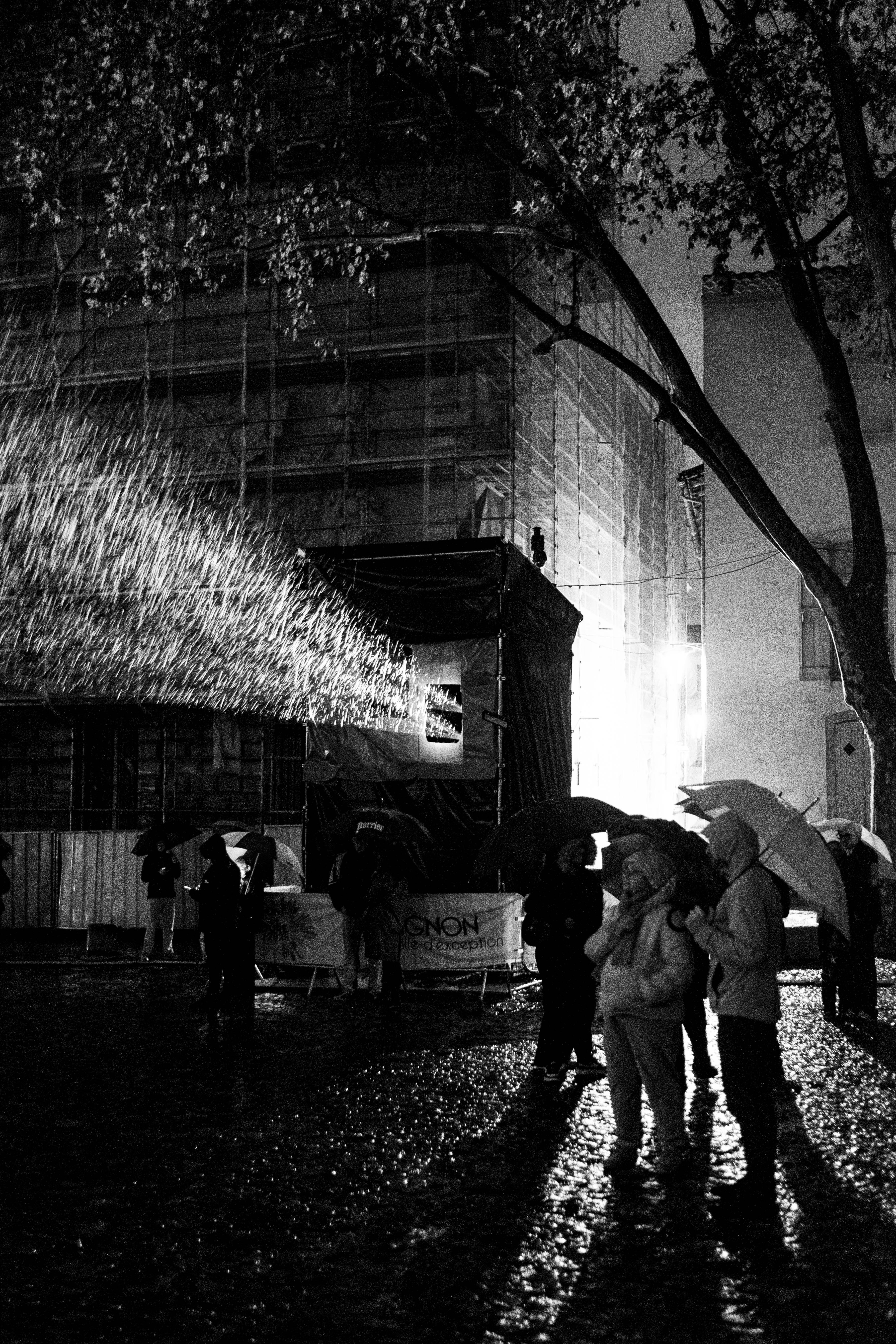 People under their umbrellas in front of an outdoor projection