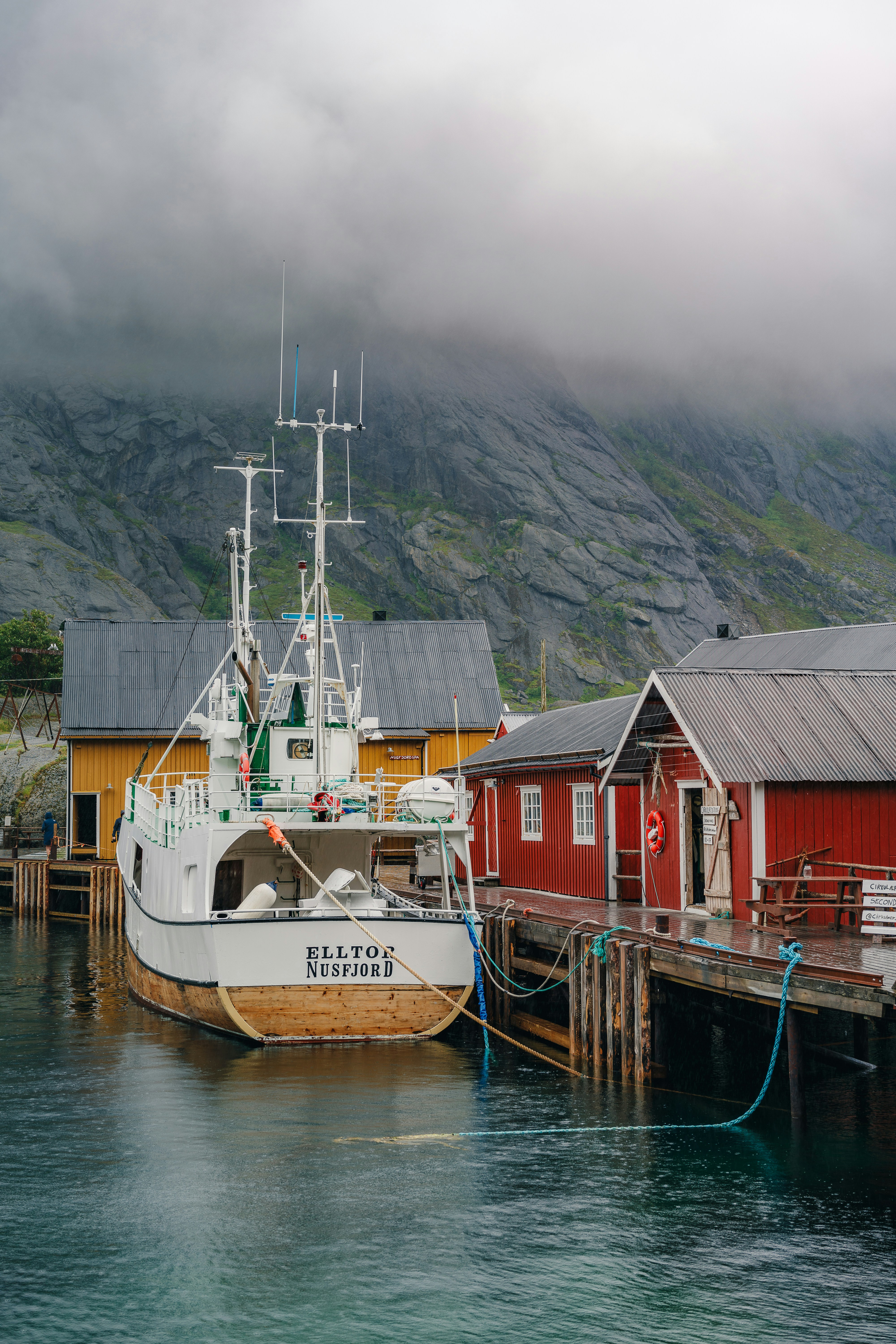 A boat docked at a dock with a mountain in the background