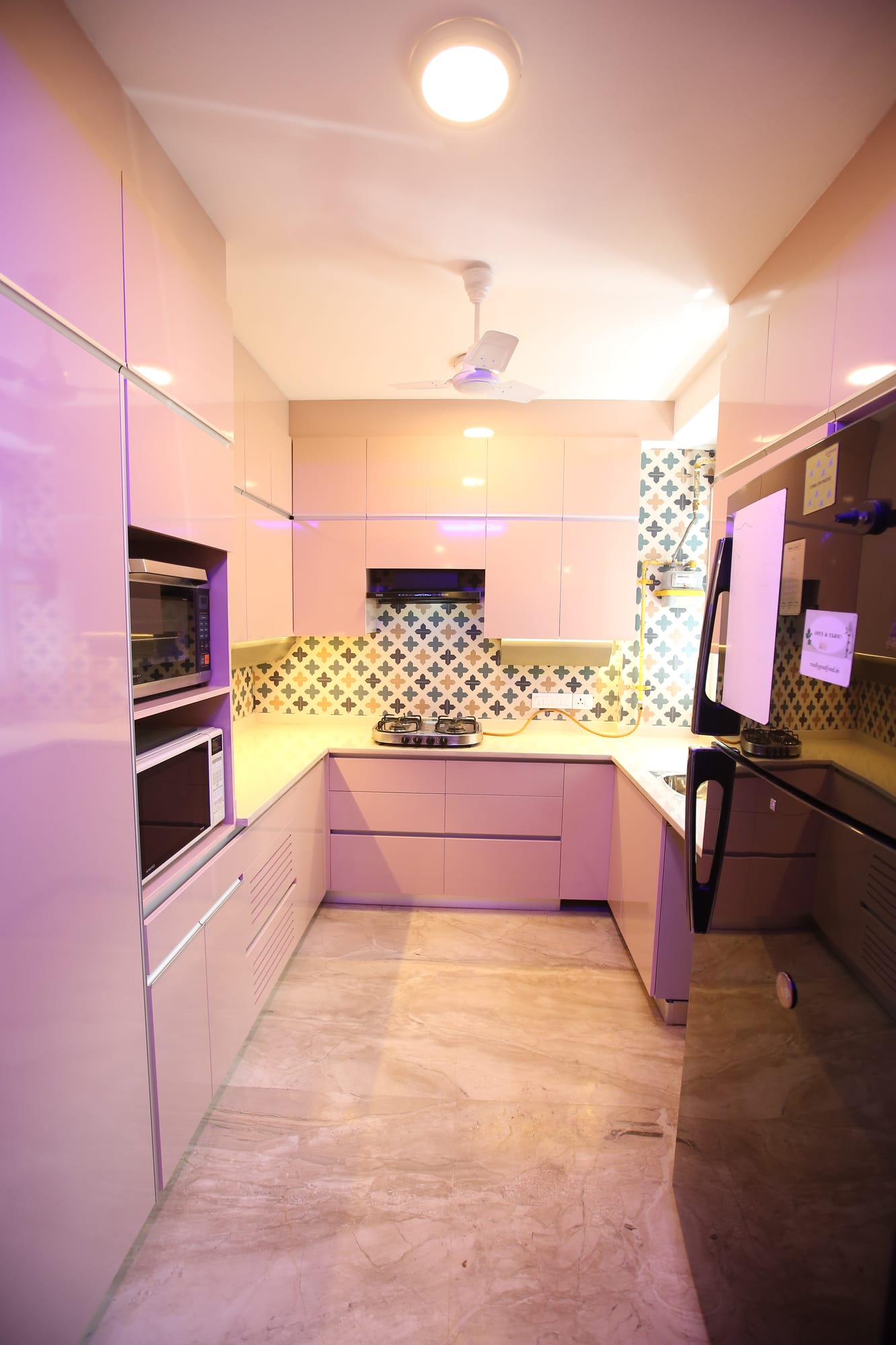 Blush-pink U-shaped modular kitchen with handleless cabinets and a patterned backsplash, Greater Kailash, New Delhi