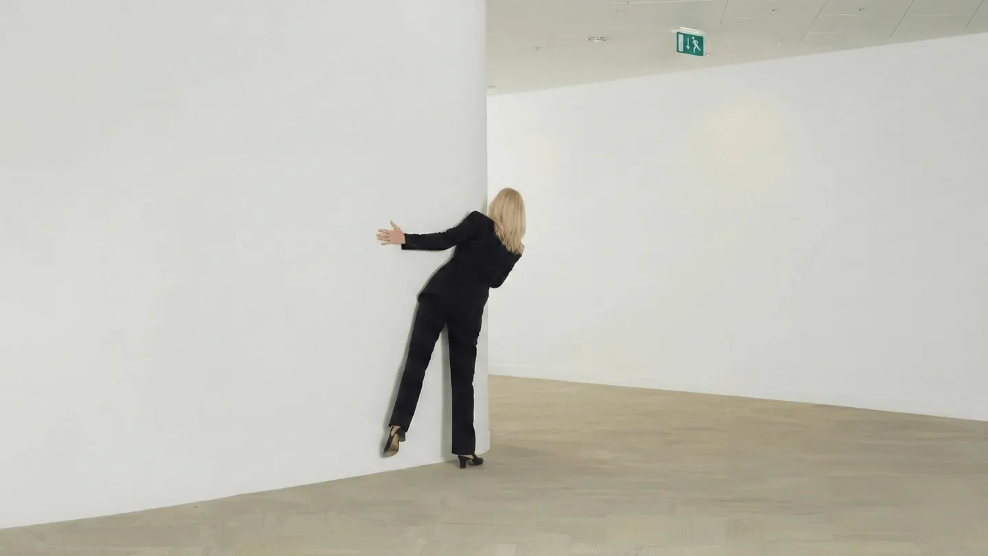 Professional reaching around corner in empty modern office space.