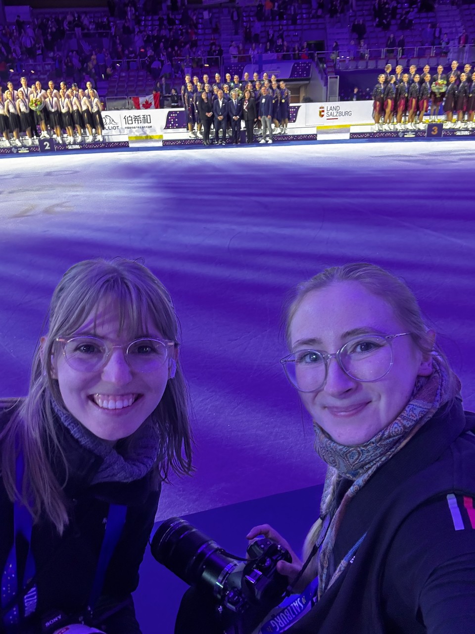 Selfie von zwei Fotografinnen auf dem Fototeppich bei der Siegerehrung der ISU Synchronized Skating Championships 2026 in Salzburg.
