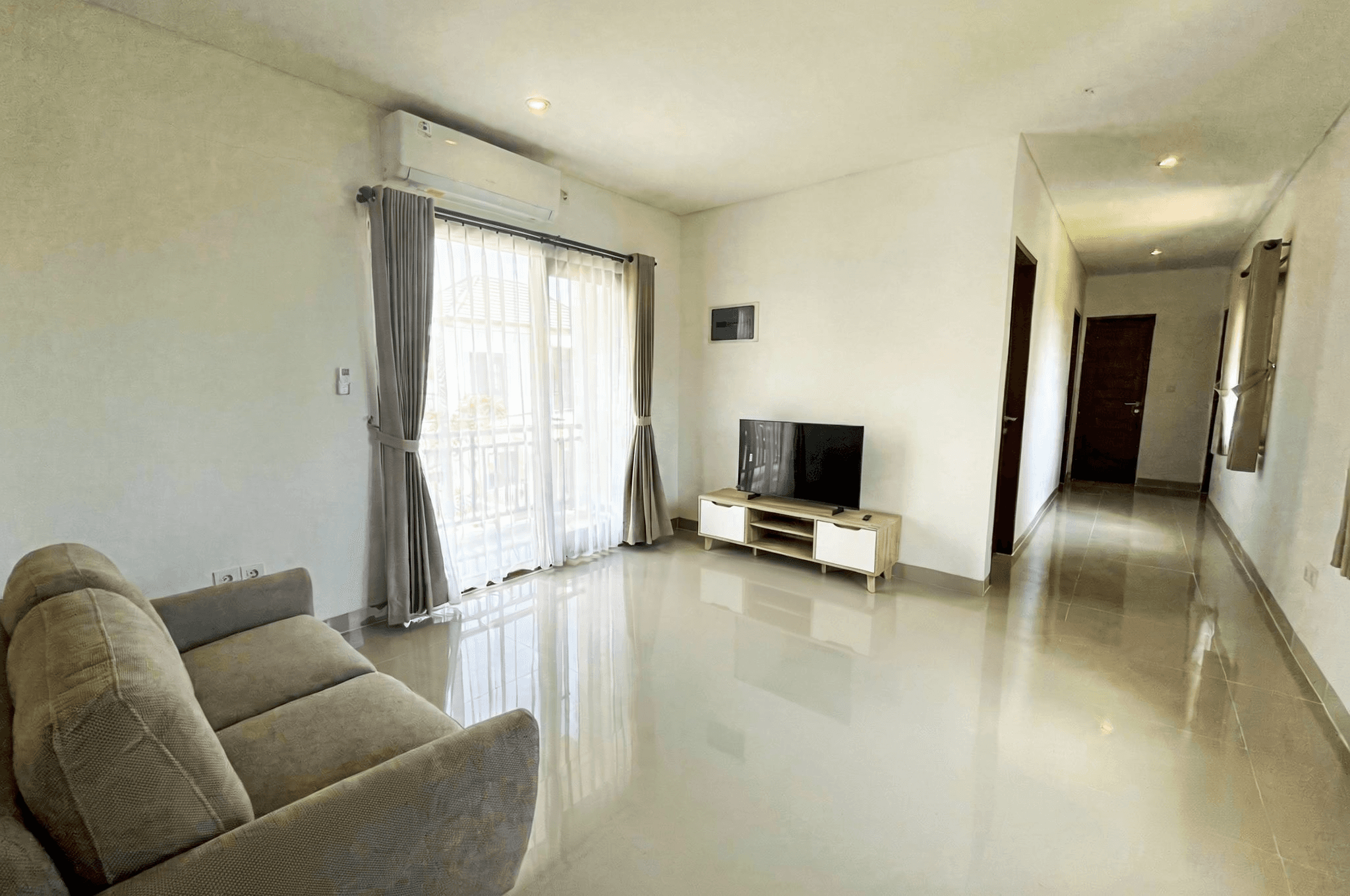 Minimalist living room with TV. Real estate agent services specializing in modern Kerobokan rentals and sales.